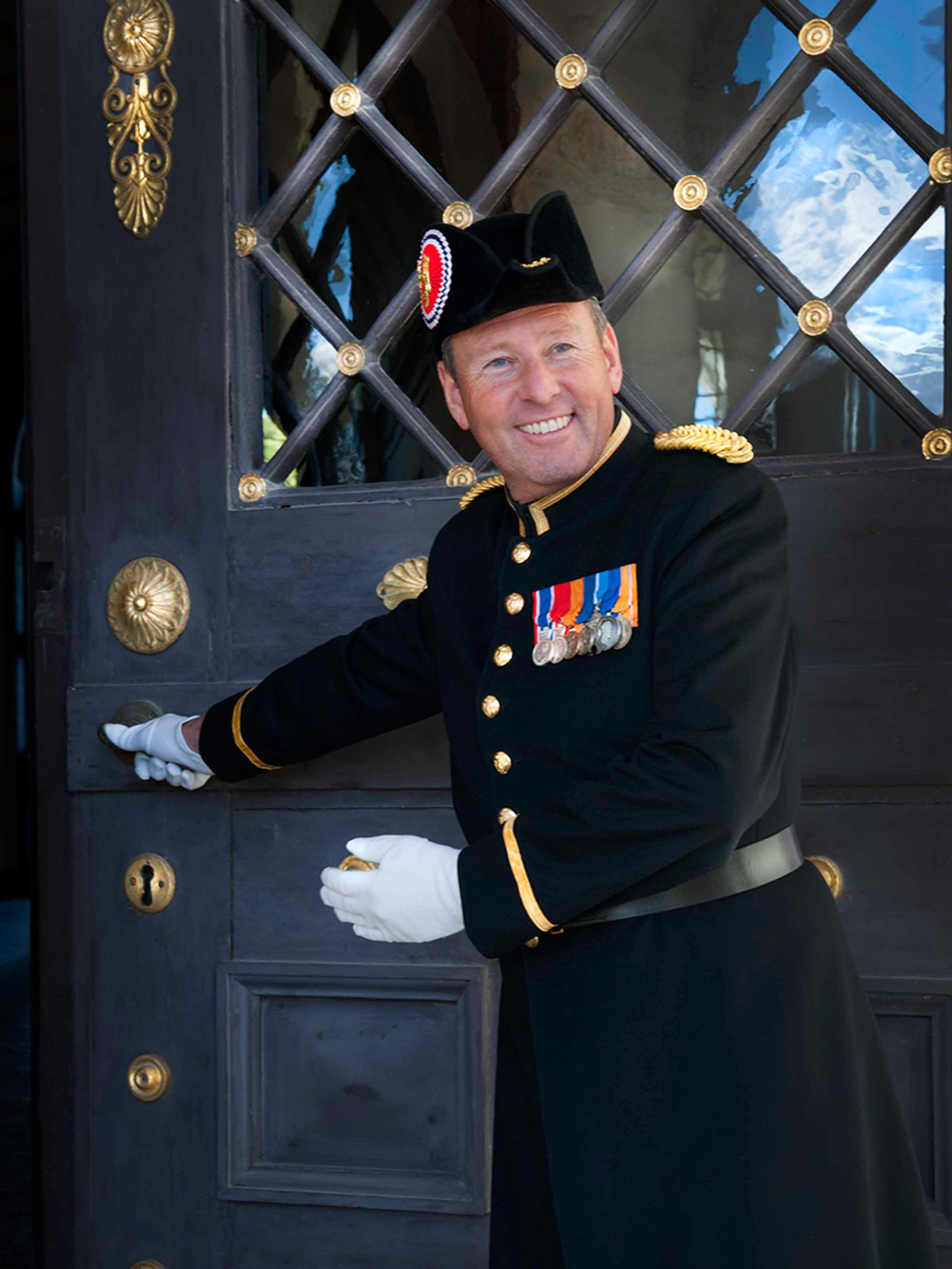 En smilende slottsknekt holder døren åpen