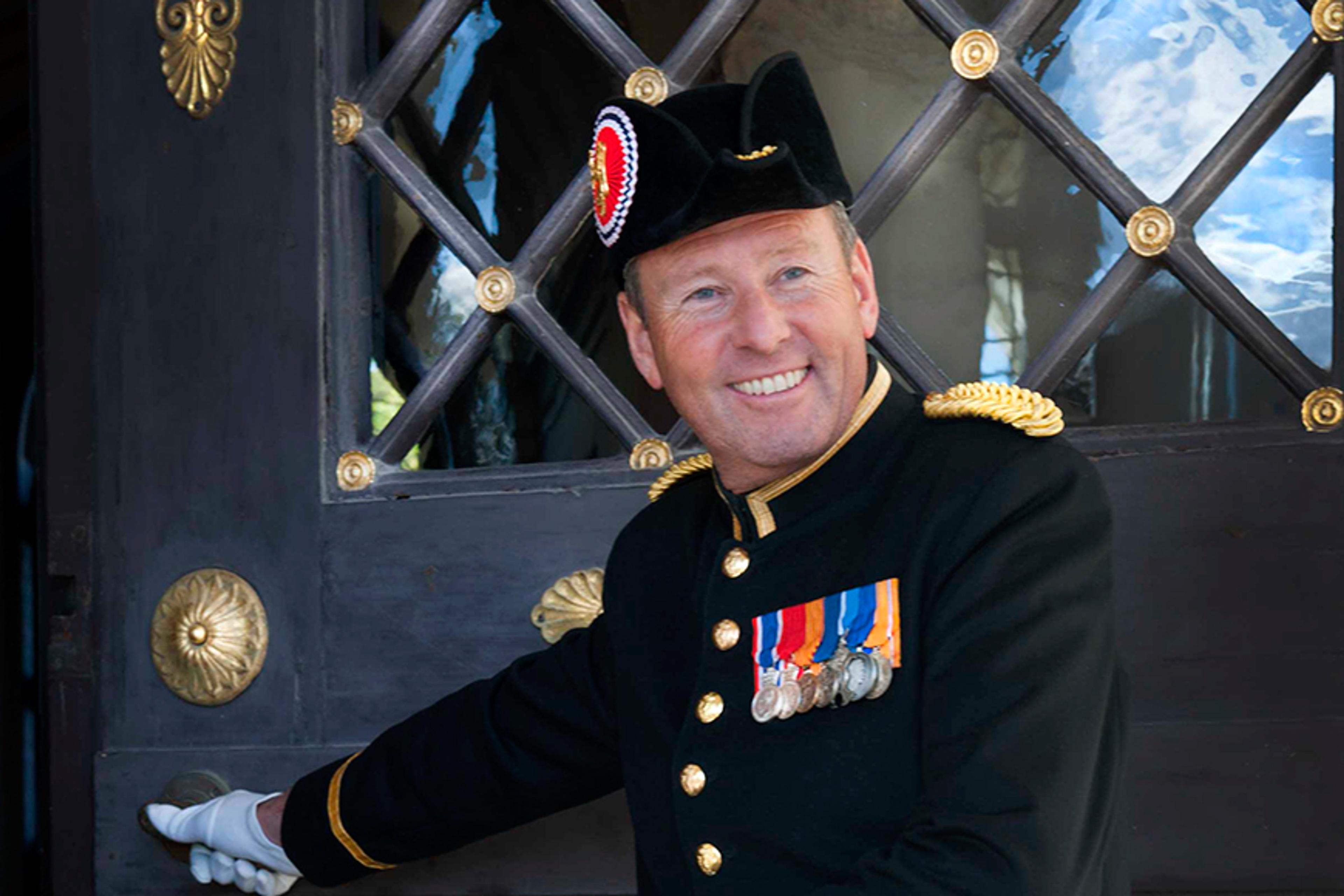 En smilende slottsknekt holder døren åpen