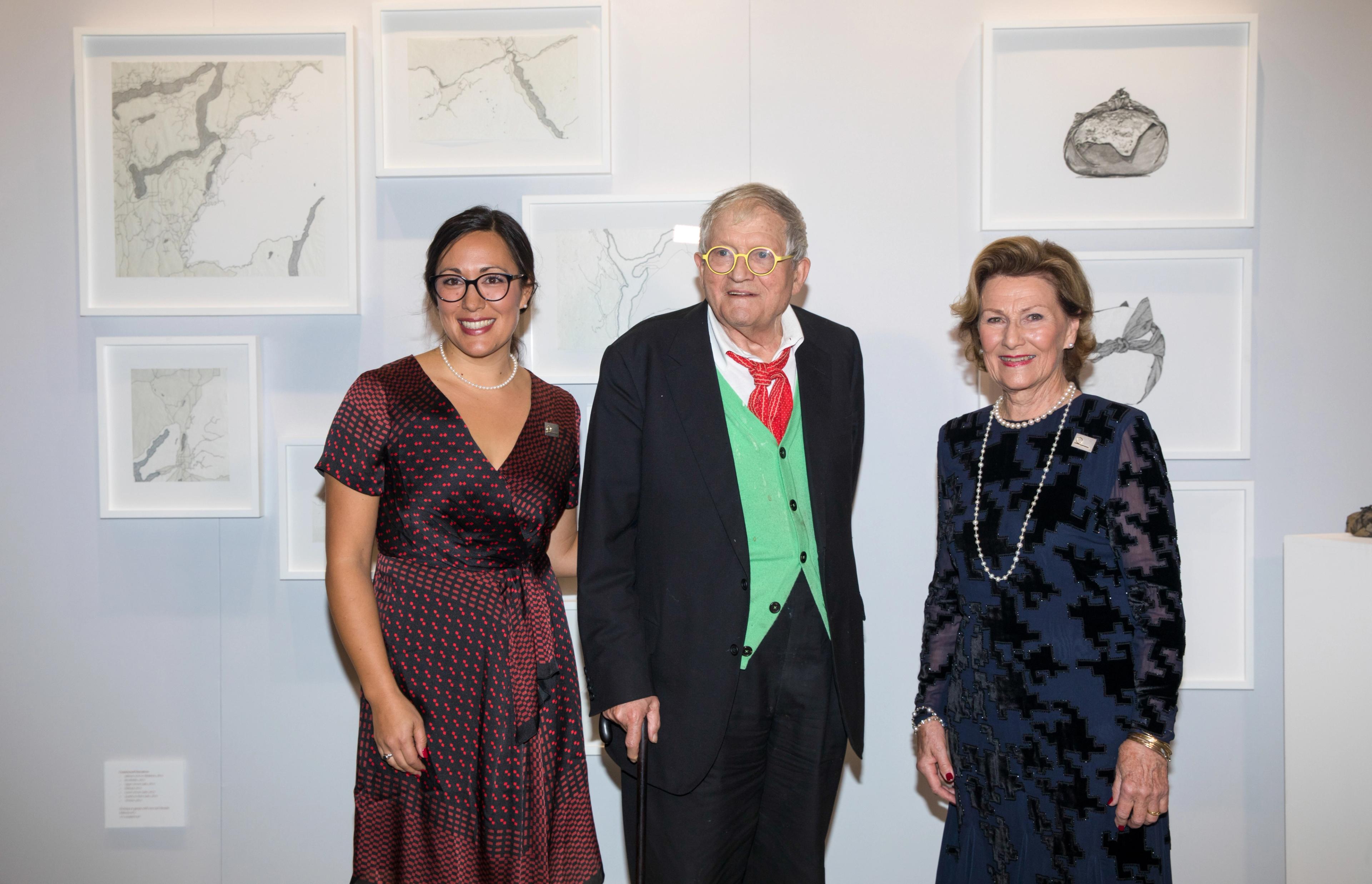 Dronning Sonja står sammen med prisvinnerne Emma Nishimura og David Hockney foran en vegg med grafiske verk.