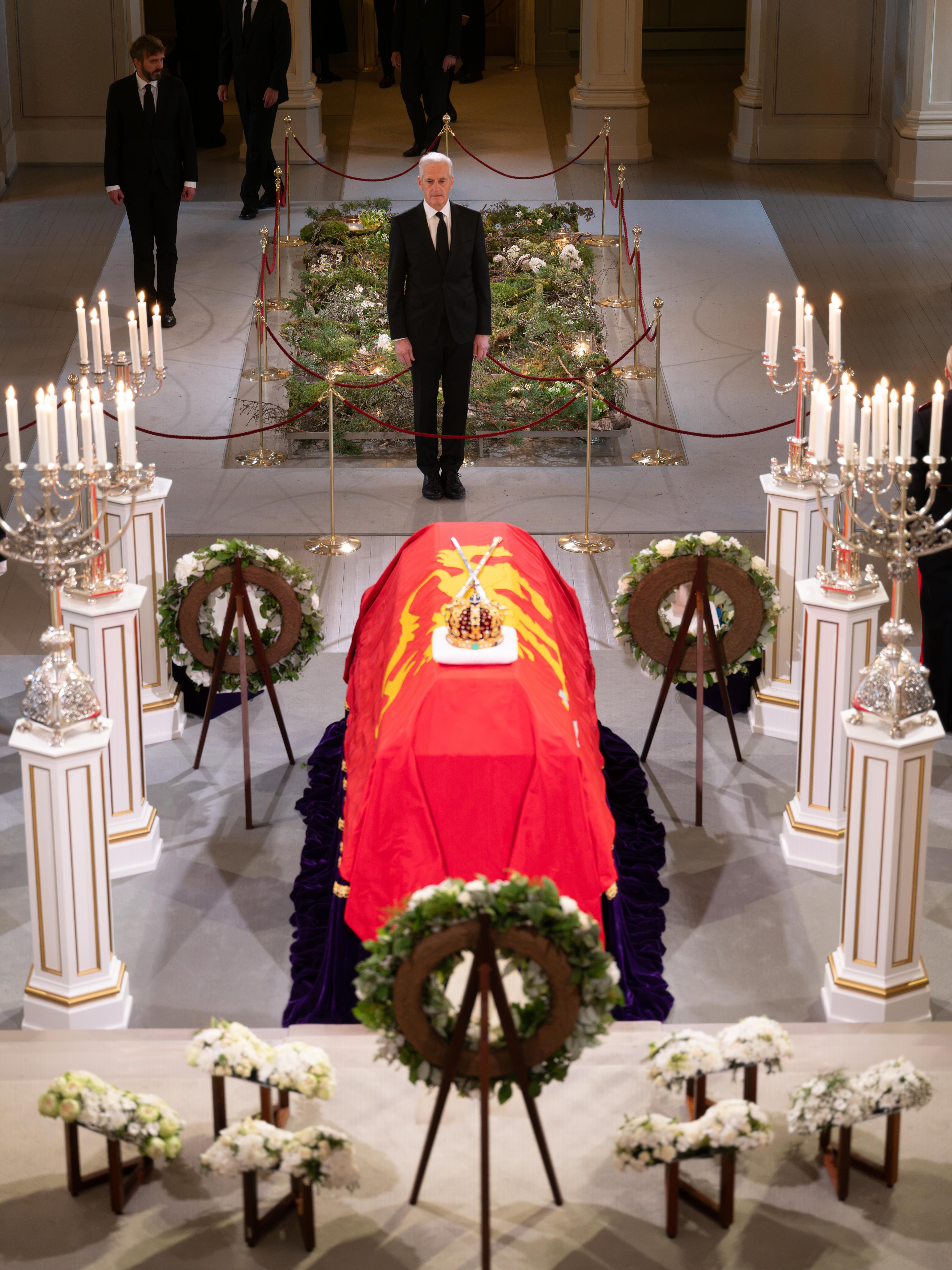 Statsministeren i sort dress foran Kong Haralds båre.