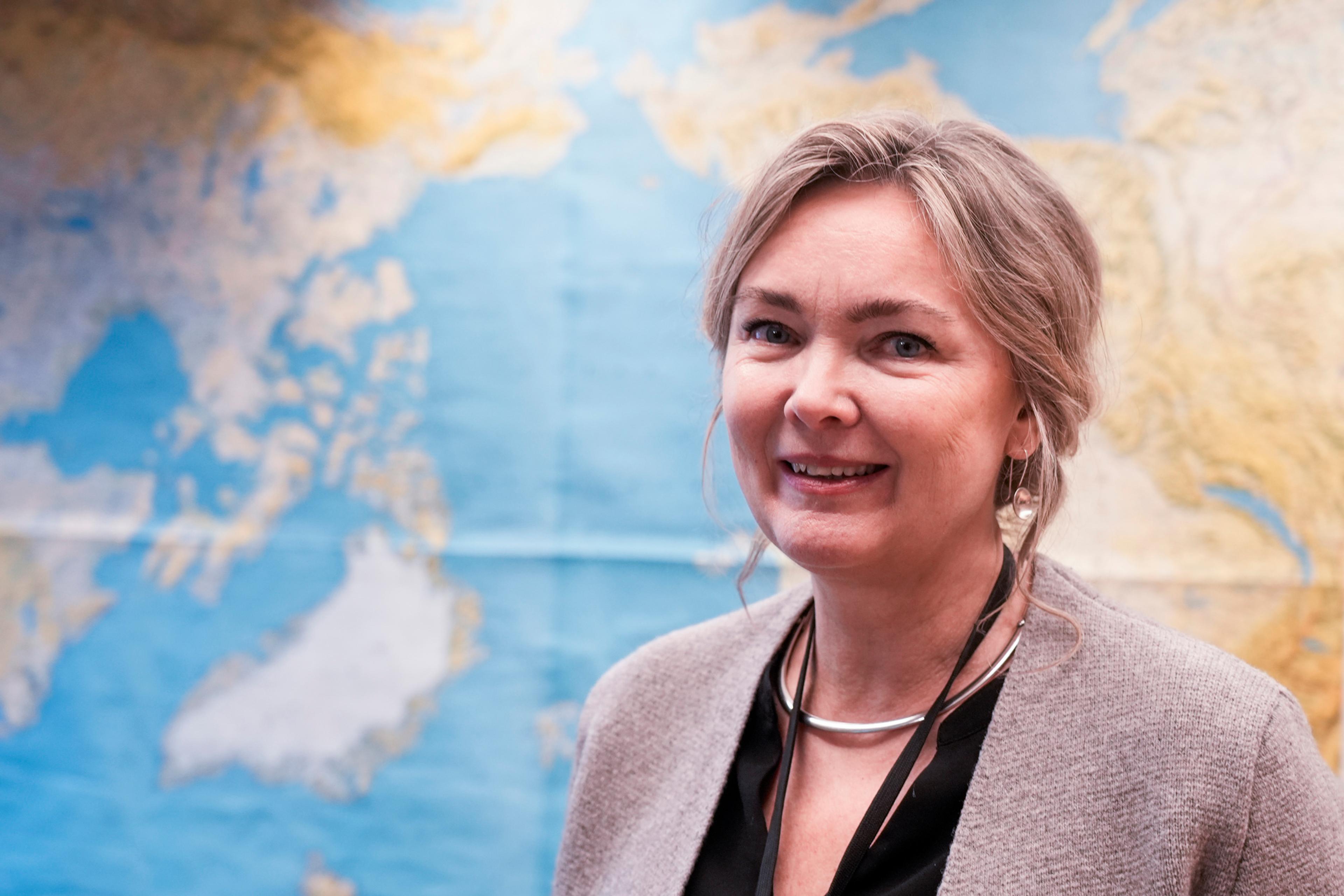 Portrettbilde av Kari M. Osland foran et verdenskart.