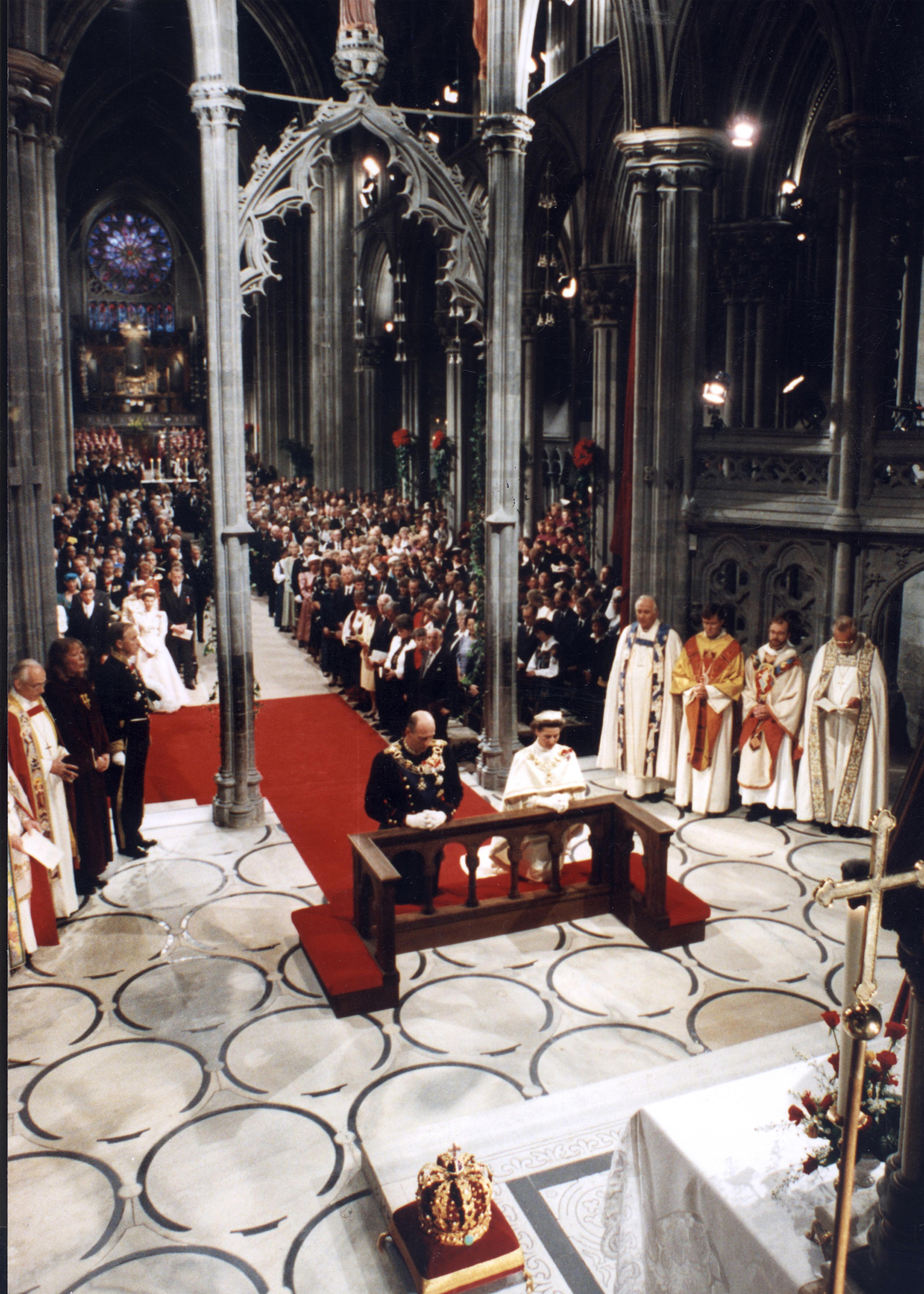 Oversiktbilde tatt foran og ovenfra, som viser deler av kirkerommet og mange stående mennesker som er til stede ved seremonien.