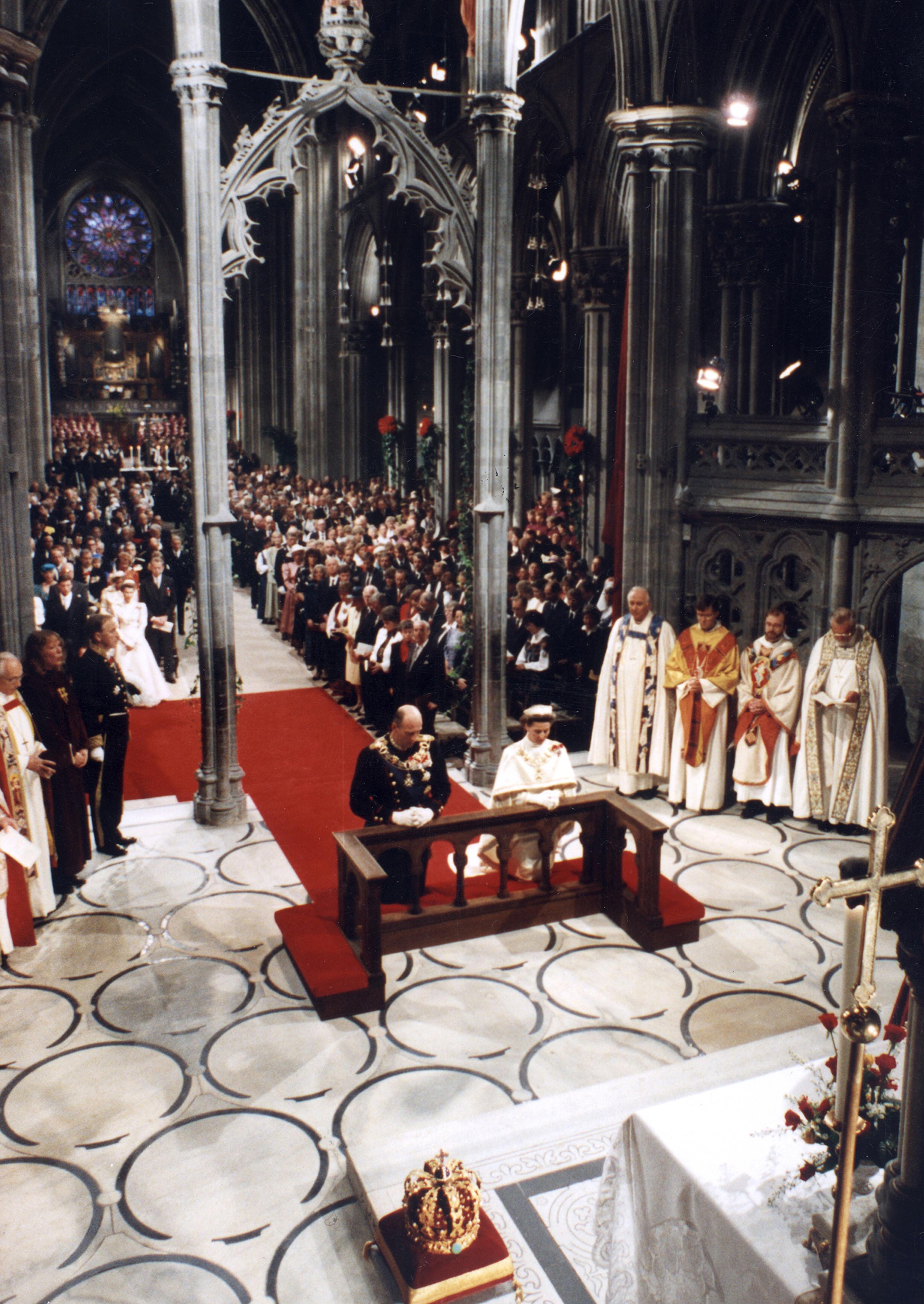 Oversiktbilde tatt foran og ovenfra, som viser deler av kirkerommet og mange stående mennesker som er til stede ved seremonien.