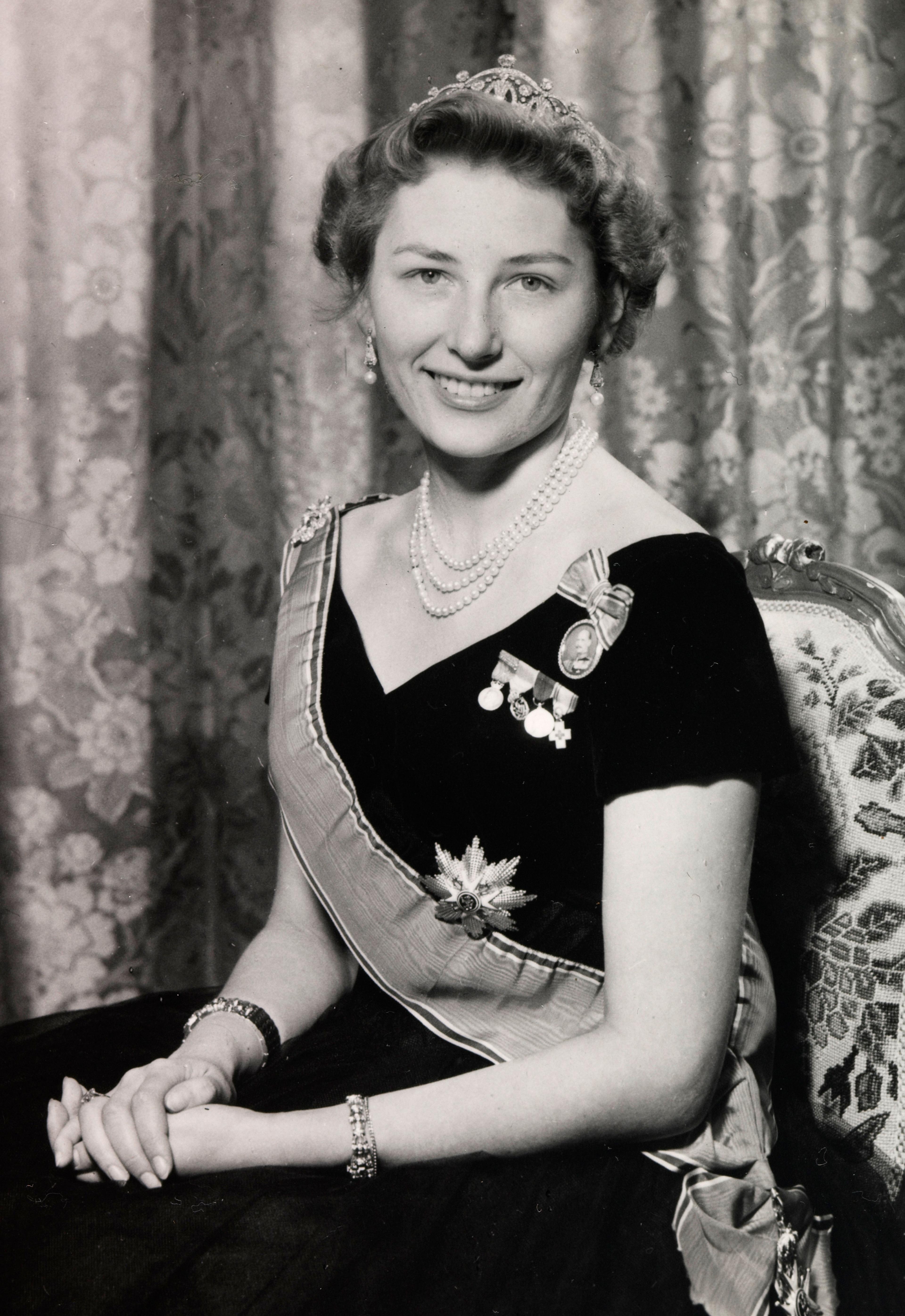 Prinsesse Astrid sitter i kjole med ordener og diadem.