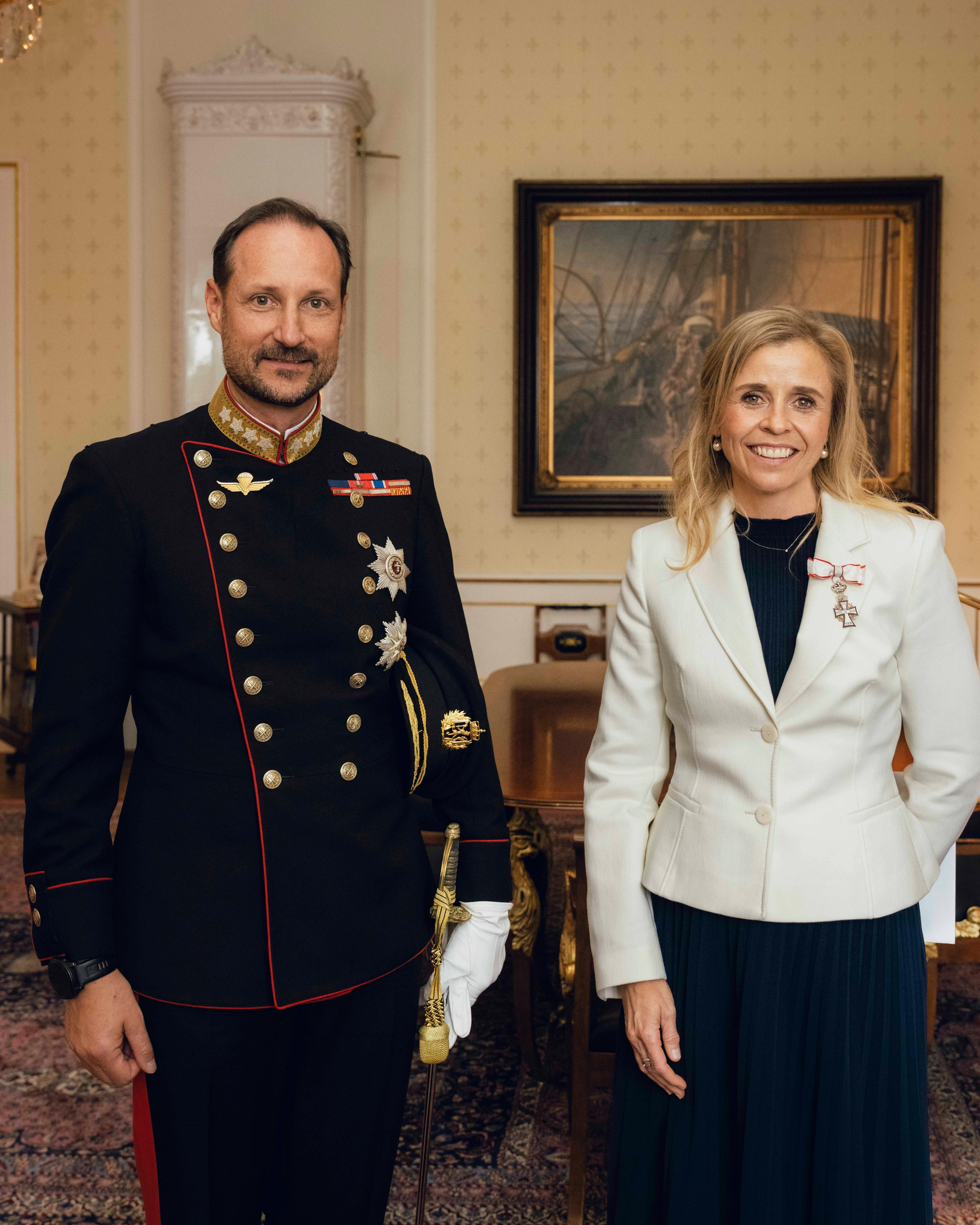 Kongen i gallauniform og ambassadøren i mørk kjole og lys jakke, står smilende ved siden av hverandre på Kongens kontor.