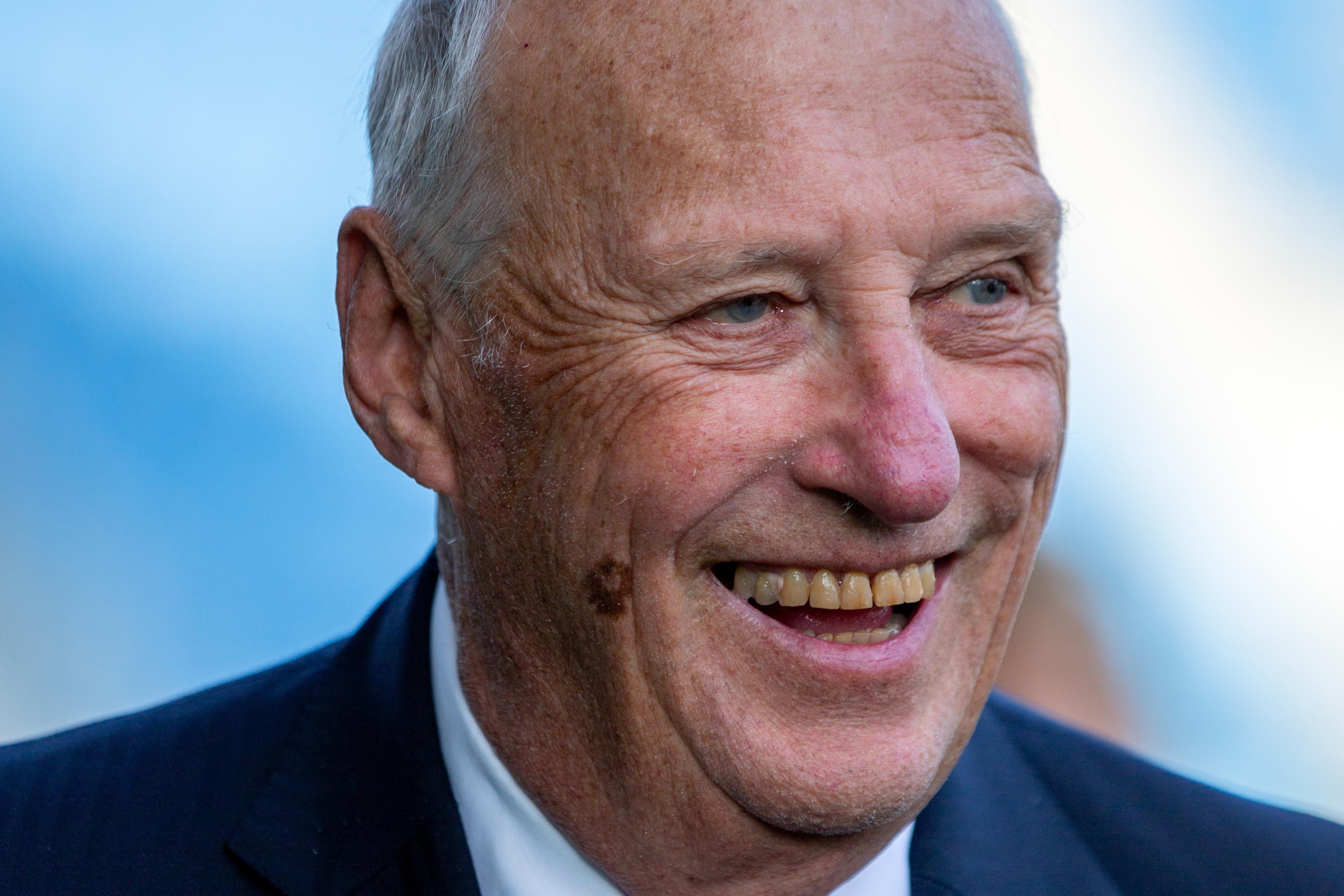 Portrettbilde av Kong Harald smilende i dress.