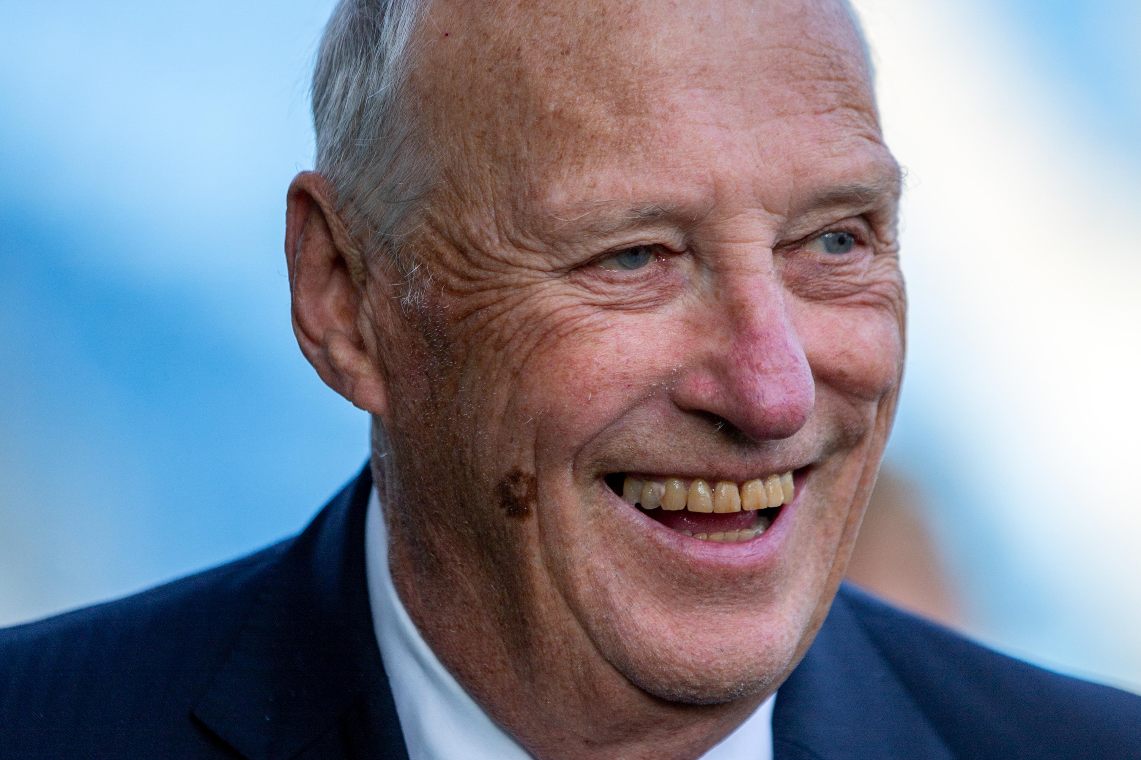 Portrettbilde av Kong Harald smilende i dress.