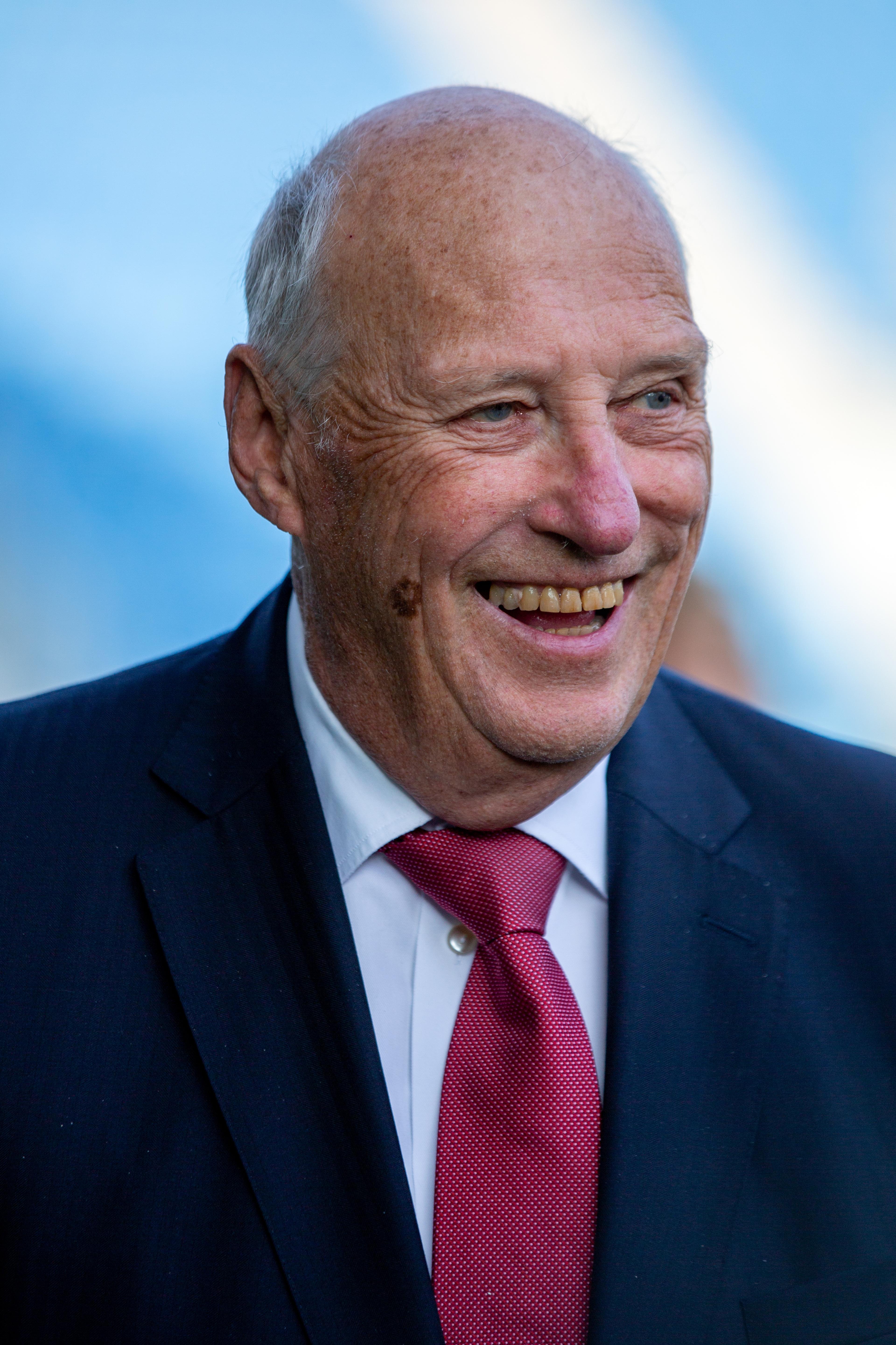 Portrettbilde av Kong Harald smilende i dress.