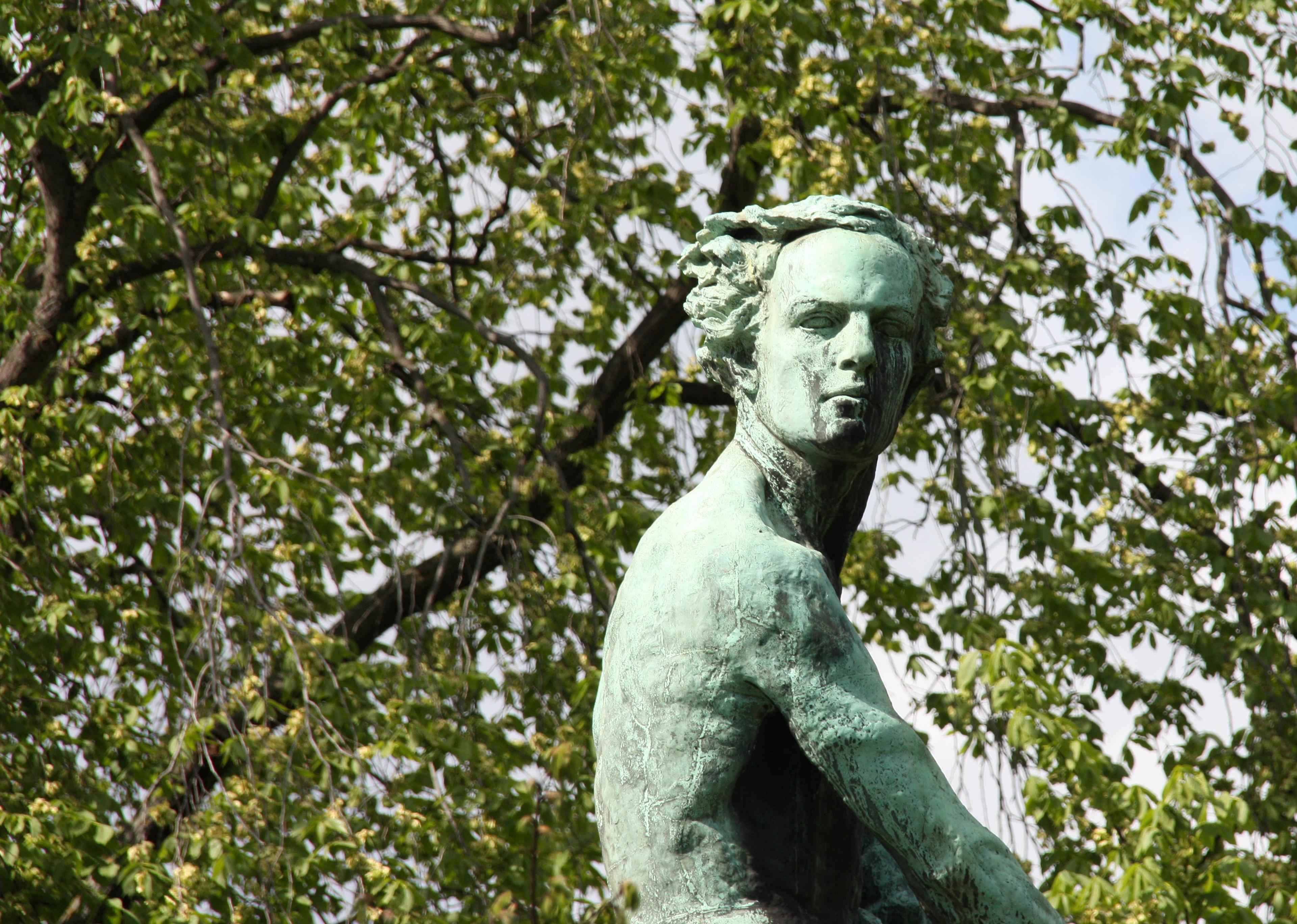 Nærbilde av statuens øverste del: en ung Abel omgitt av vårgrønne trær.