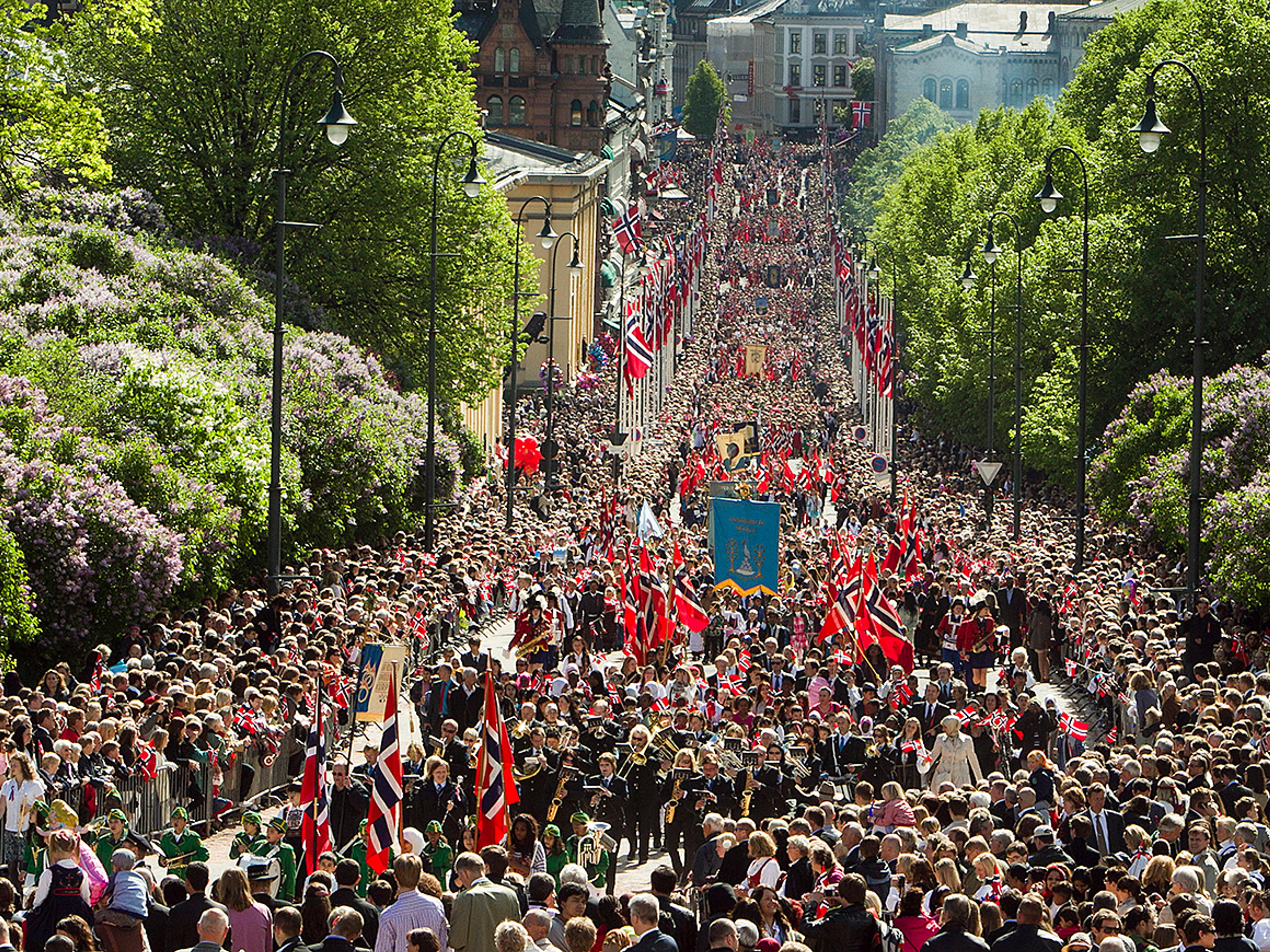 En fargerik elv av barn og flagg velter oppover Slottsbakken på vei mot Slottet. 