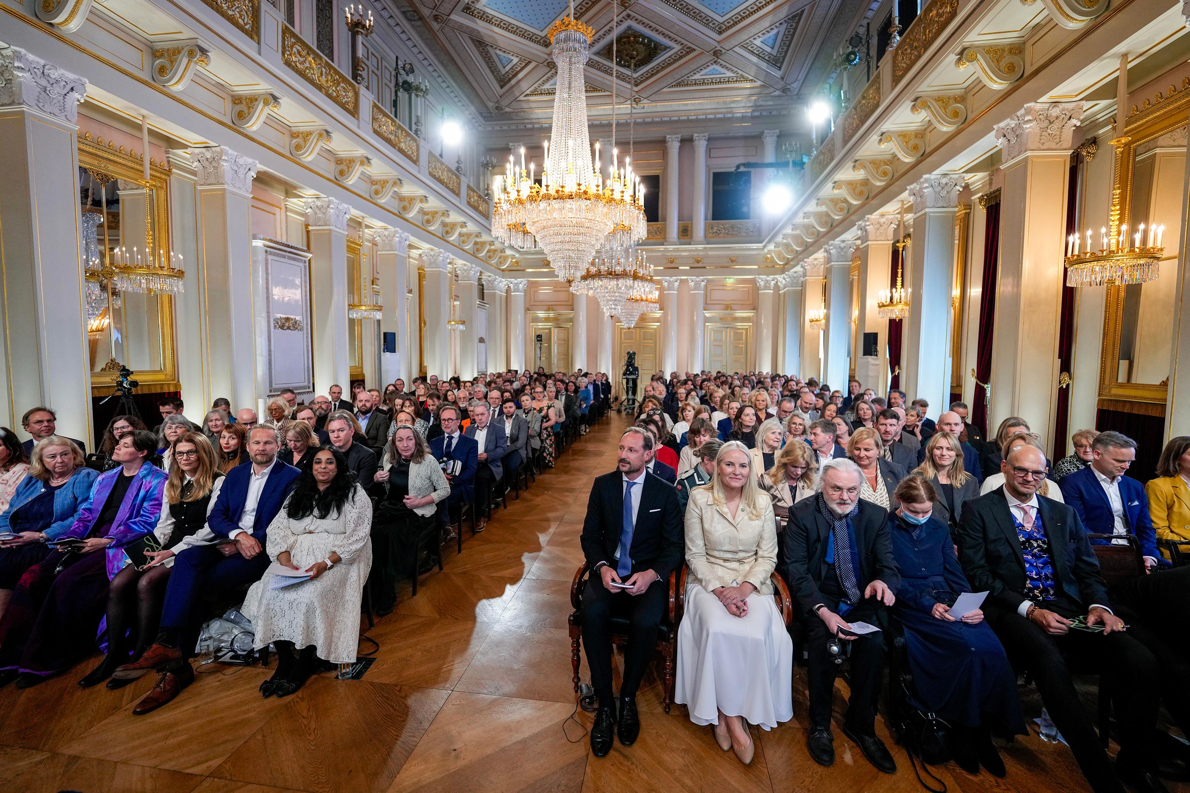 Store festsal er full av mennesker som venter på at arrangementet starter. Kronprinsparet sitter sammen med Jon Fosse på første rad.