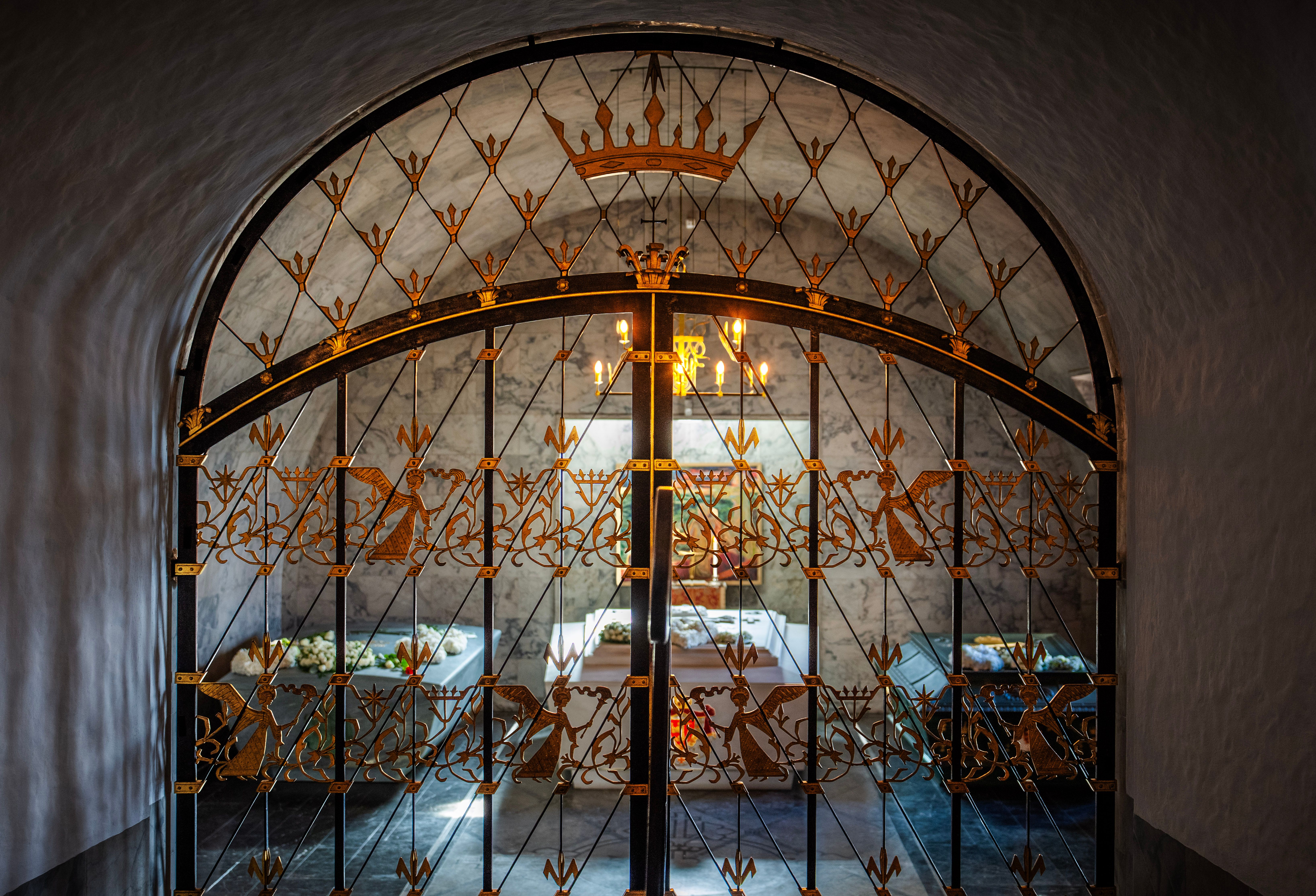 De tre sarkofagene i Det kongelige mausoleum sett gjennom en utsmykket gitterdør inn til mausoleet.