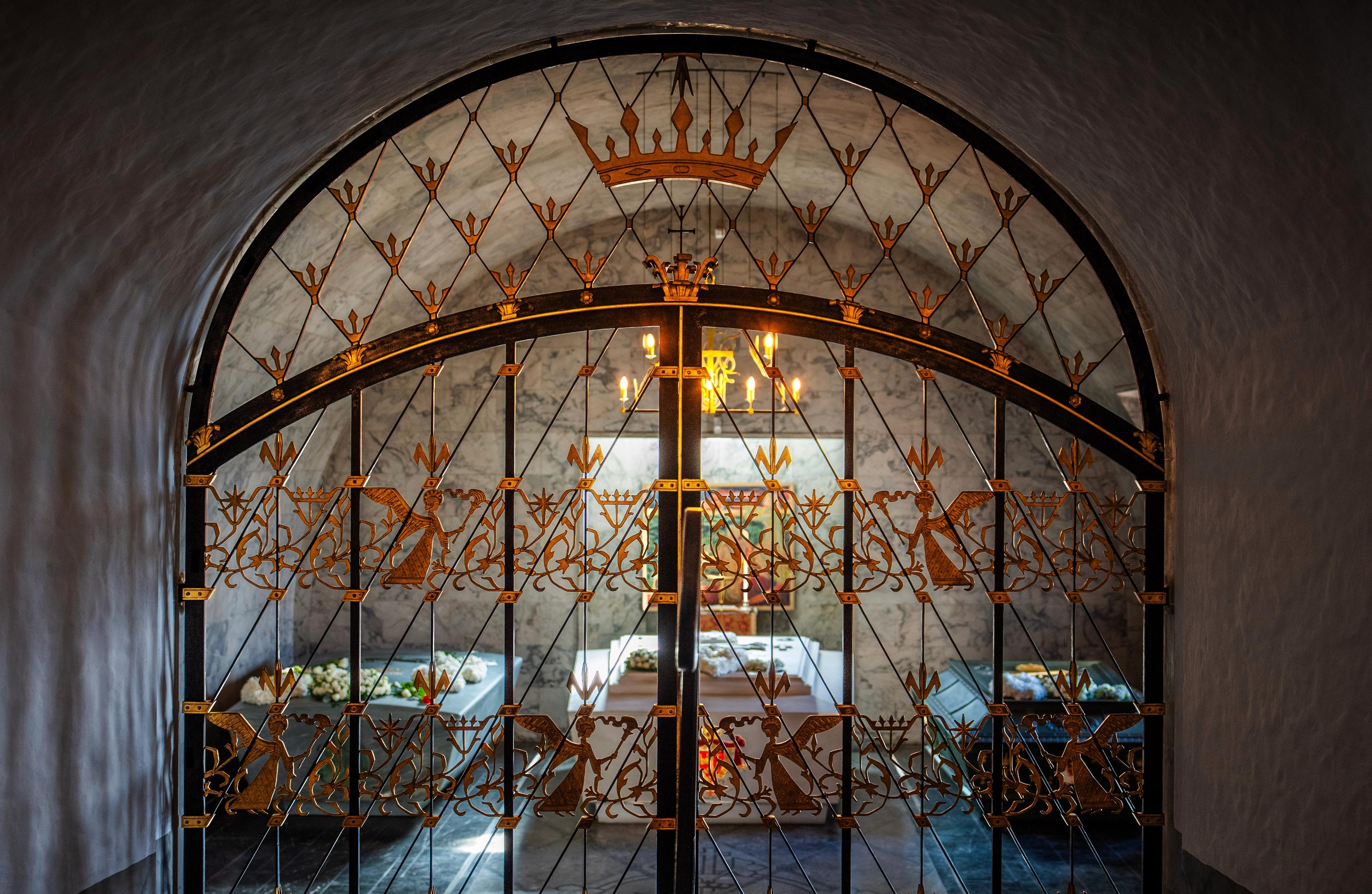 De tre sarkofagene i Det kongelige mausoleum sett gjennom en utsmykket gitterdør inn til mausoleet.