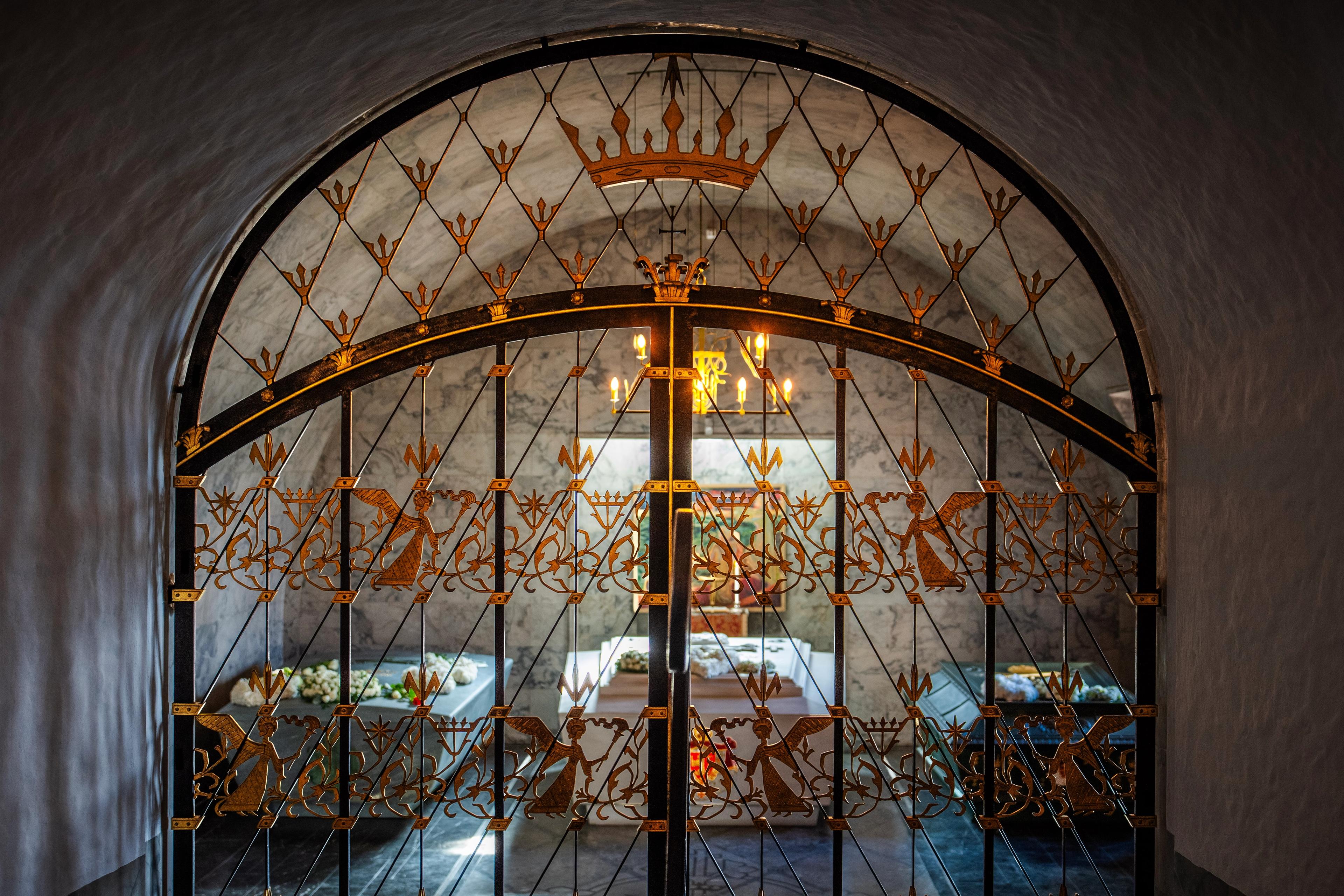 De tre sarkofagene i Det kongelige mausoleum sett gjennom en utsmykket gitterdør inn til mausoleet.