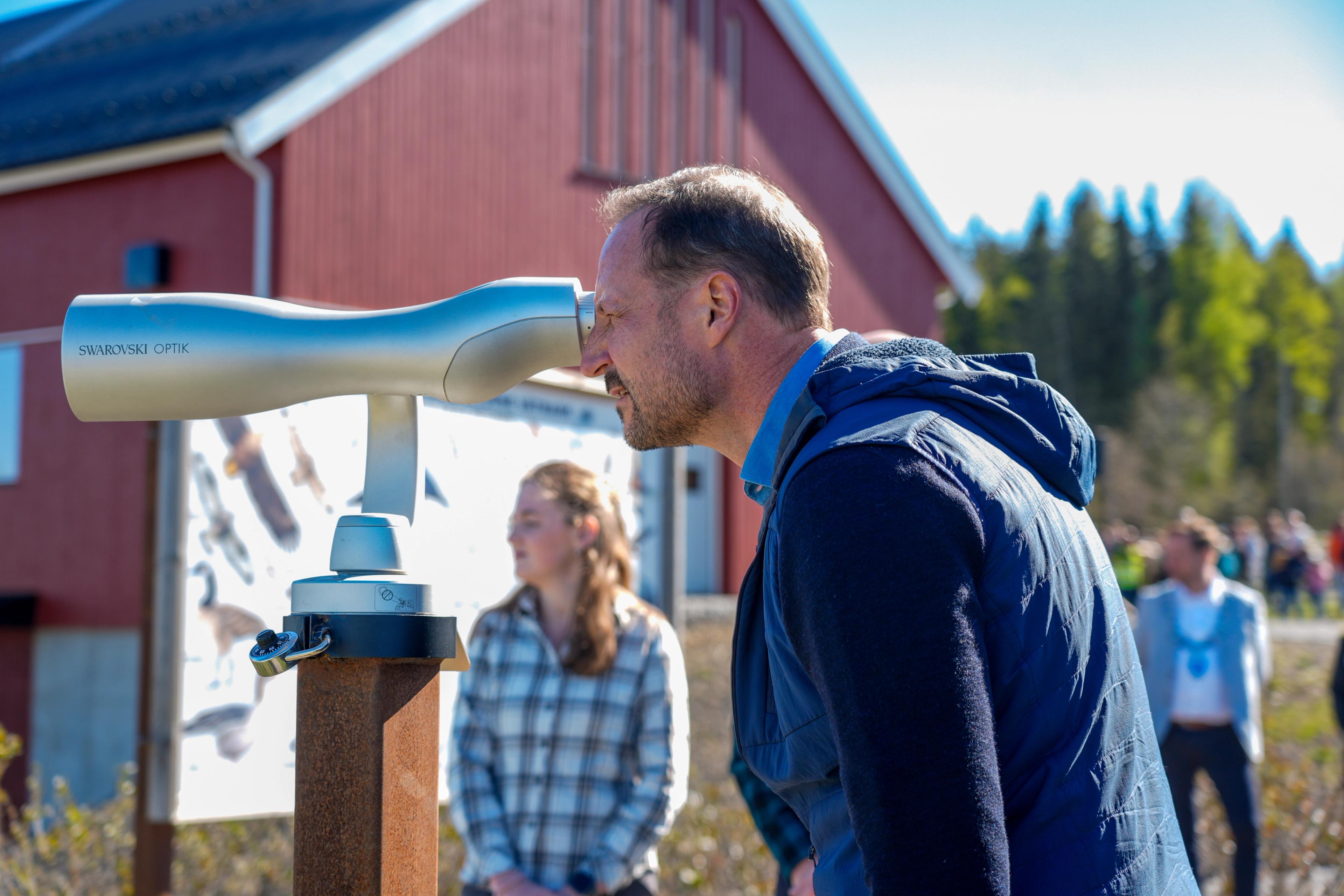 Kronprins Haakon kikker inn i en fuglekikkert.