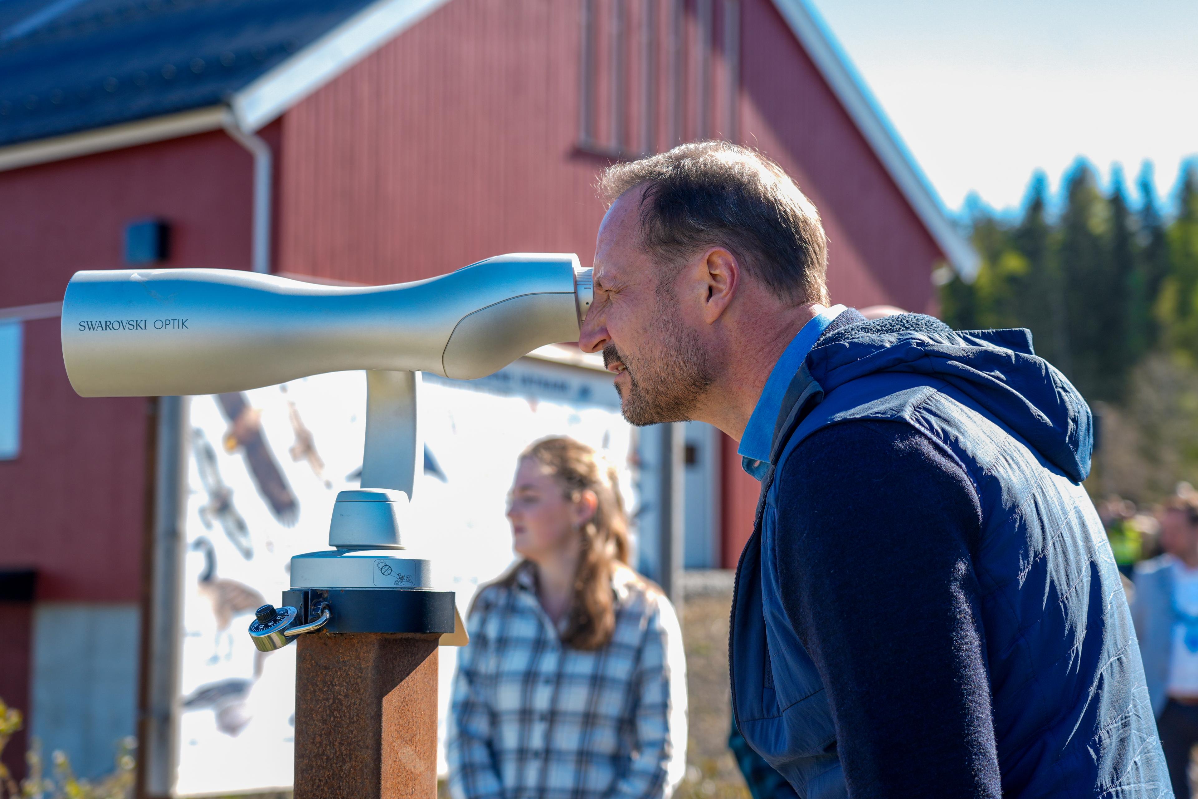 Kronprins Haakon kikker inn i en fuglekikkert.