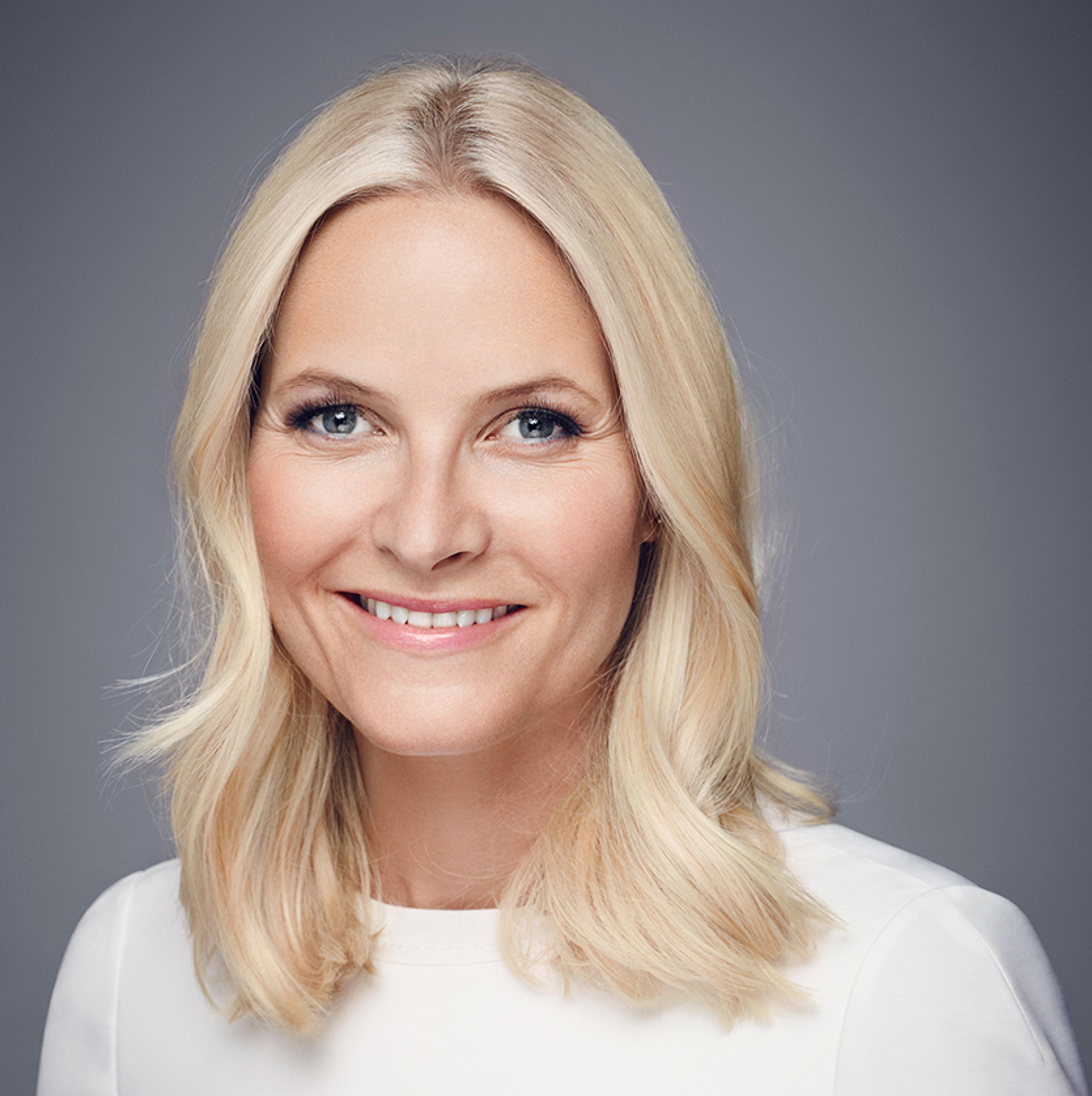 Portrett av Kronprinsessen. Hun har hvit genser og ser smilende inn i kameraet.