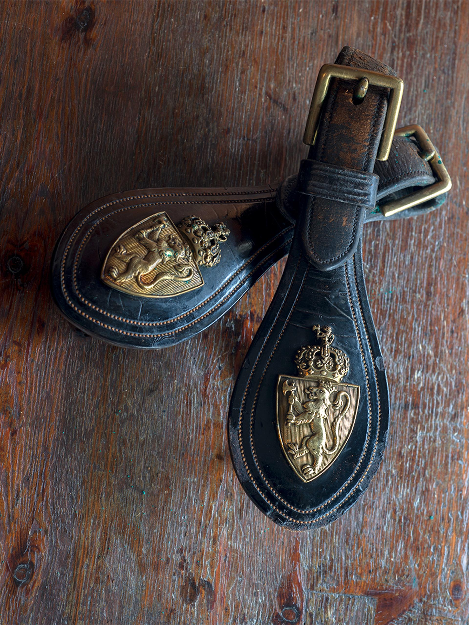 Nærbilde av spenner preget med riksvåpenet.