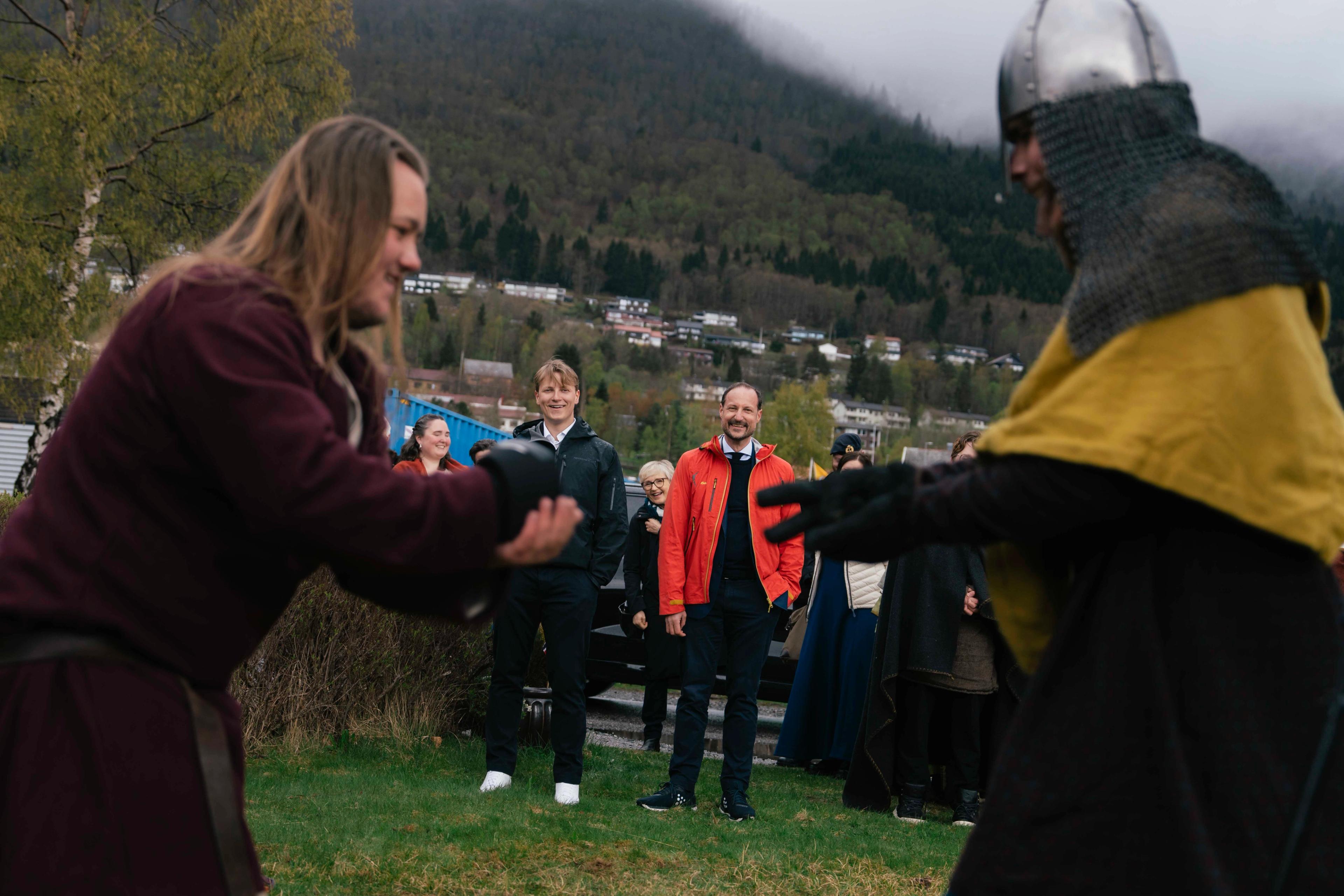 To elever fra Fjordane Folkehøgskule er kledd i vikingklær og har en opptreden foran Kronprins Haakon og Prins Sverre Magnus, som sees i bakgrunnen. De befinner seg utendørs
