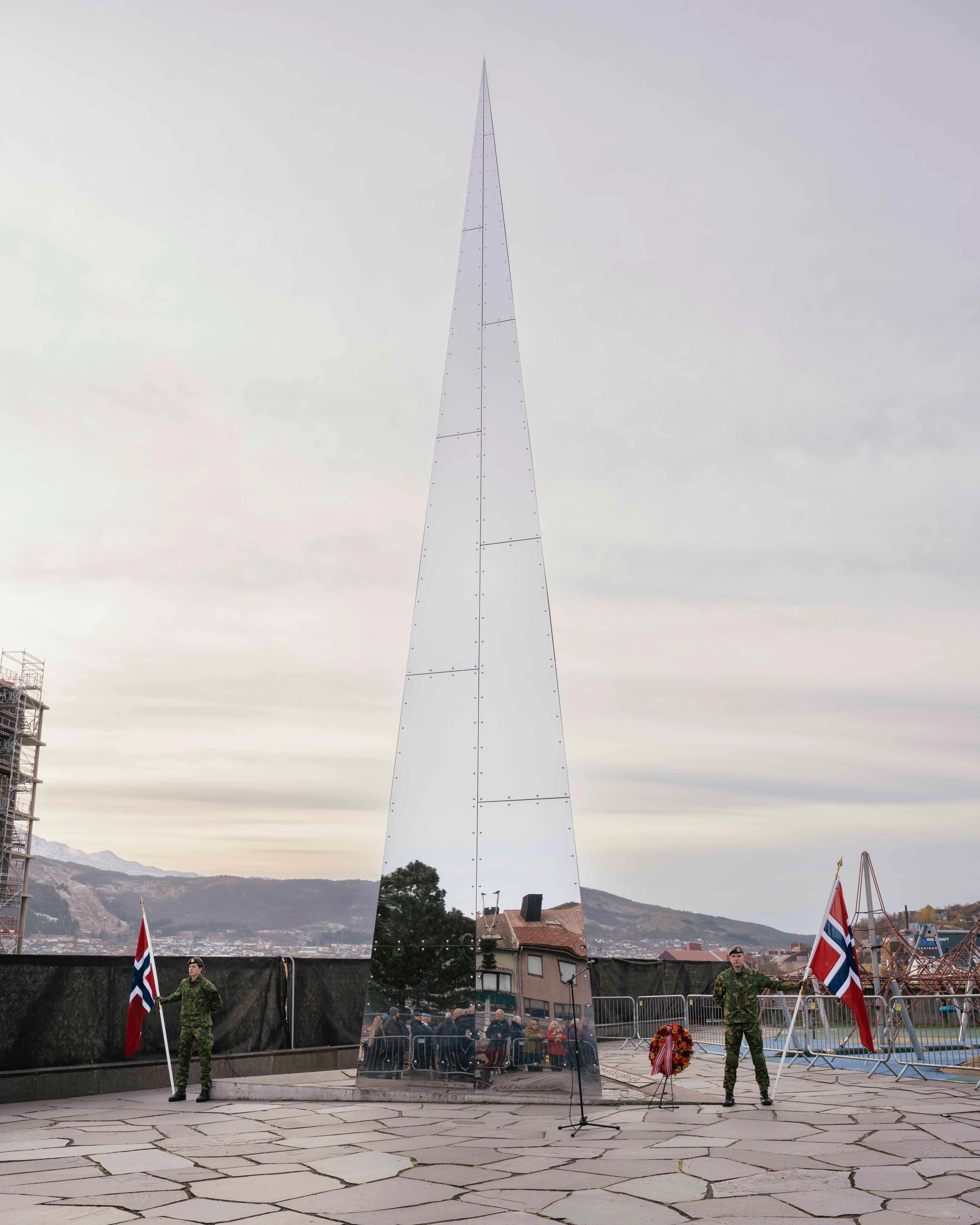 Et triangelformet monument med speilmateriale står plassert utenfor Narviksenteret