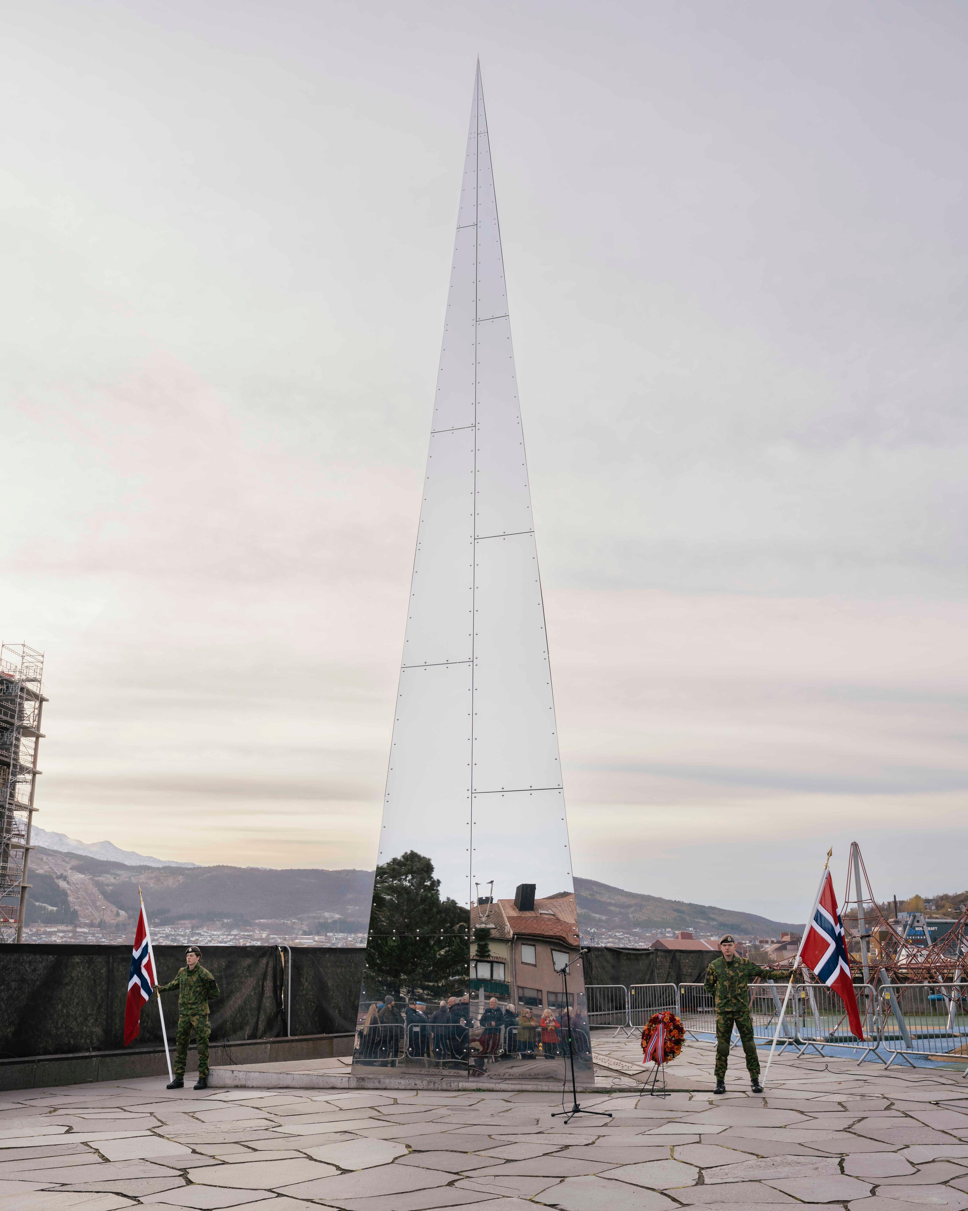 Et triangelformet monument med speilmateriale står plassert utenfor Narviksenteret