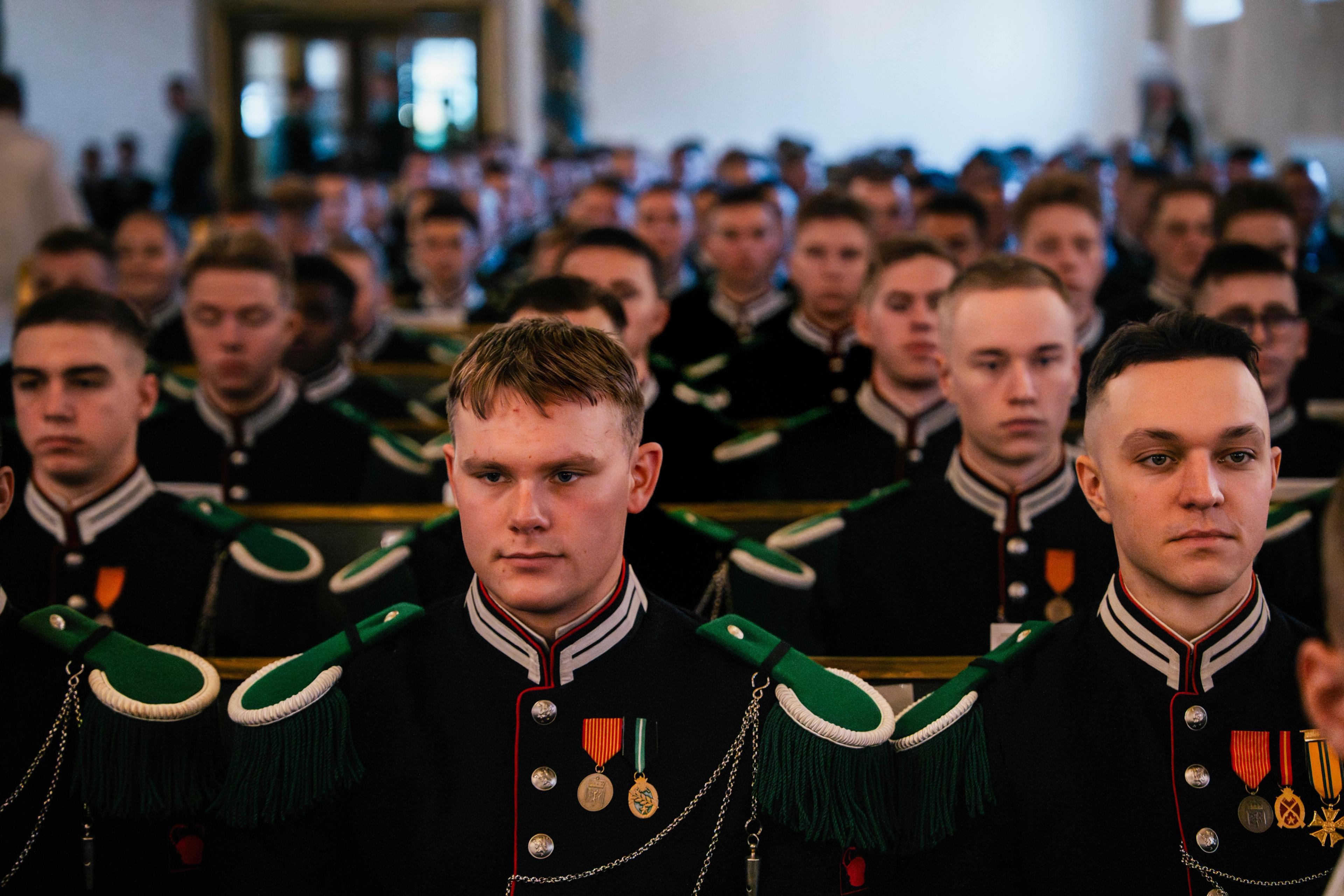 Gardister forfra sittende på kirkebenker.