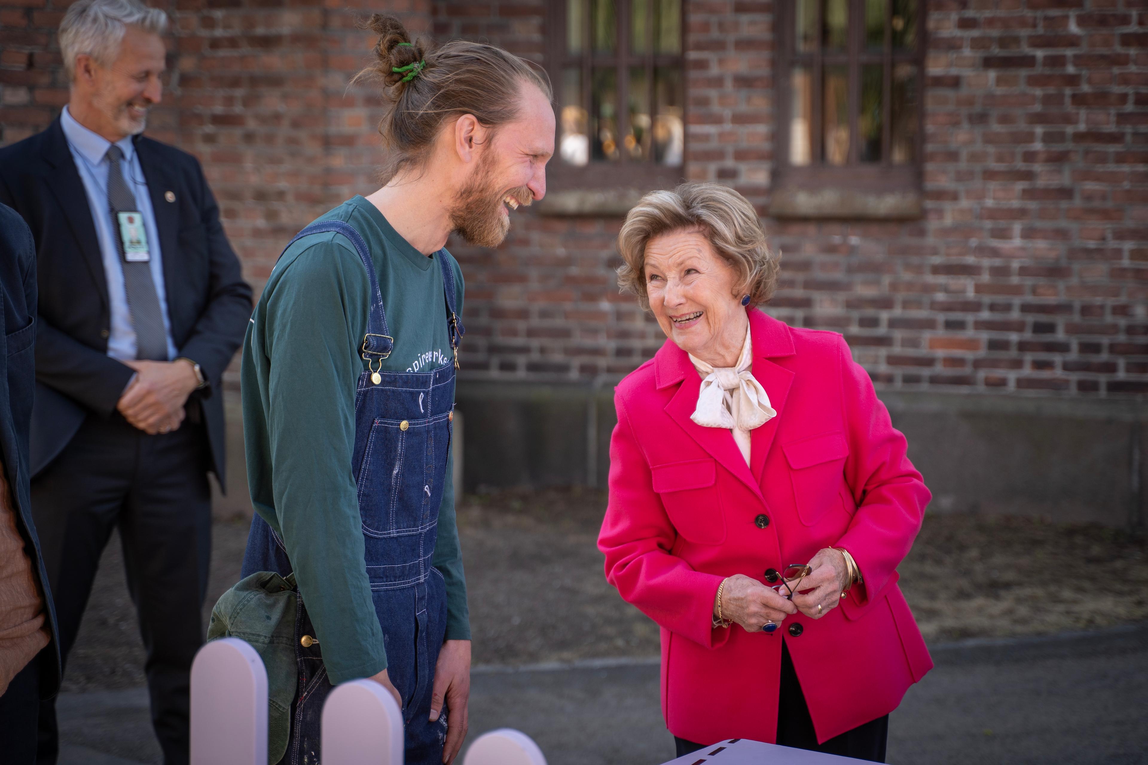 Dronningen og Olav Sæterbakken smiler i samtale med hverandre.