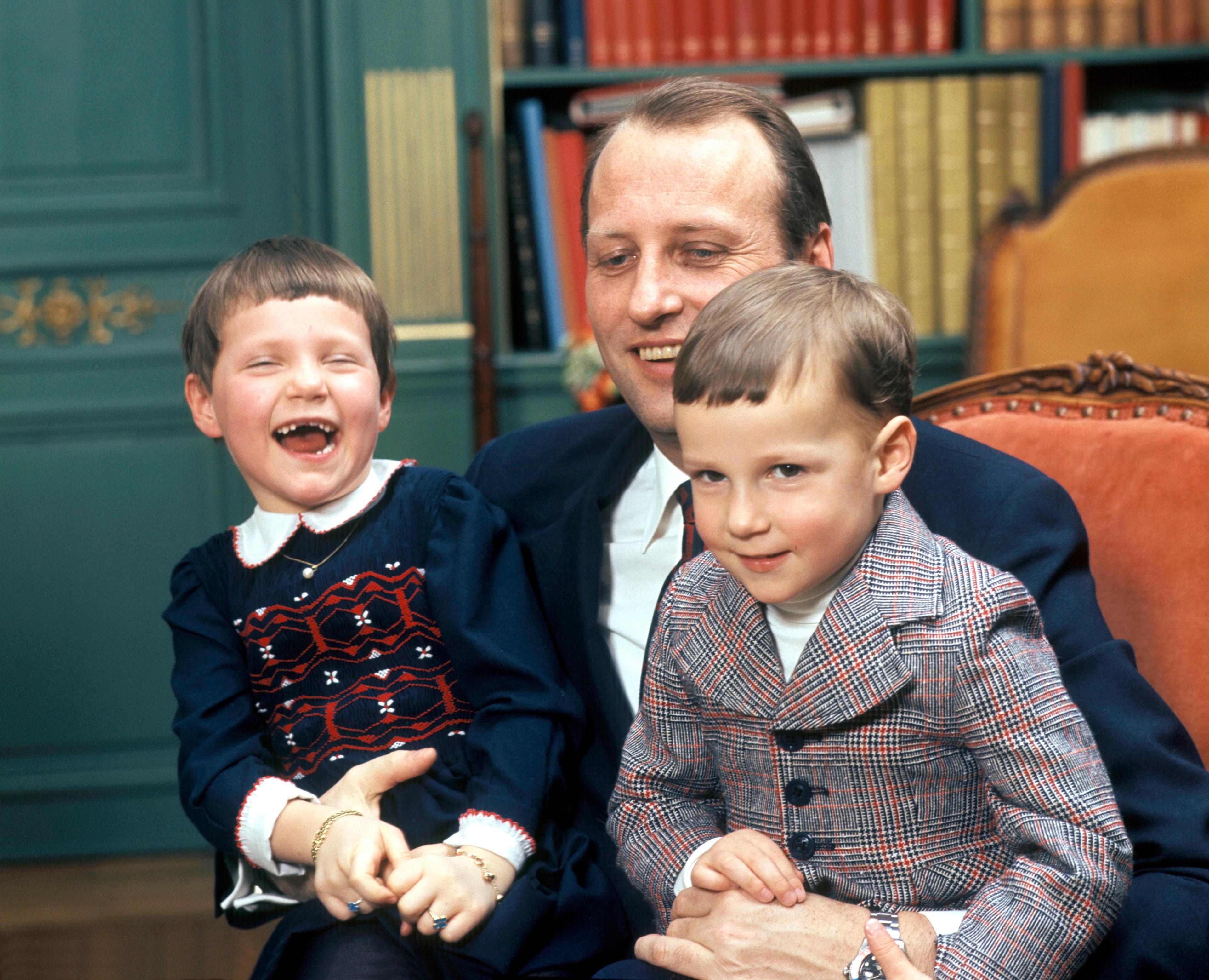 Prinsesse Märtha Louise og Prins Haakon Magnus sitter på fanget til faren, Kronprins Harald.