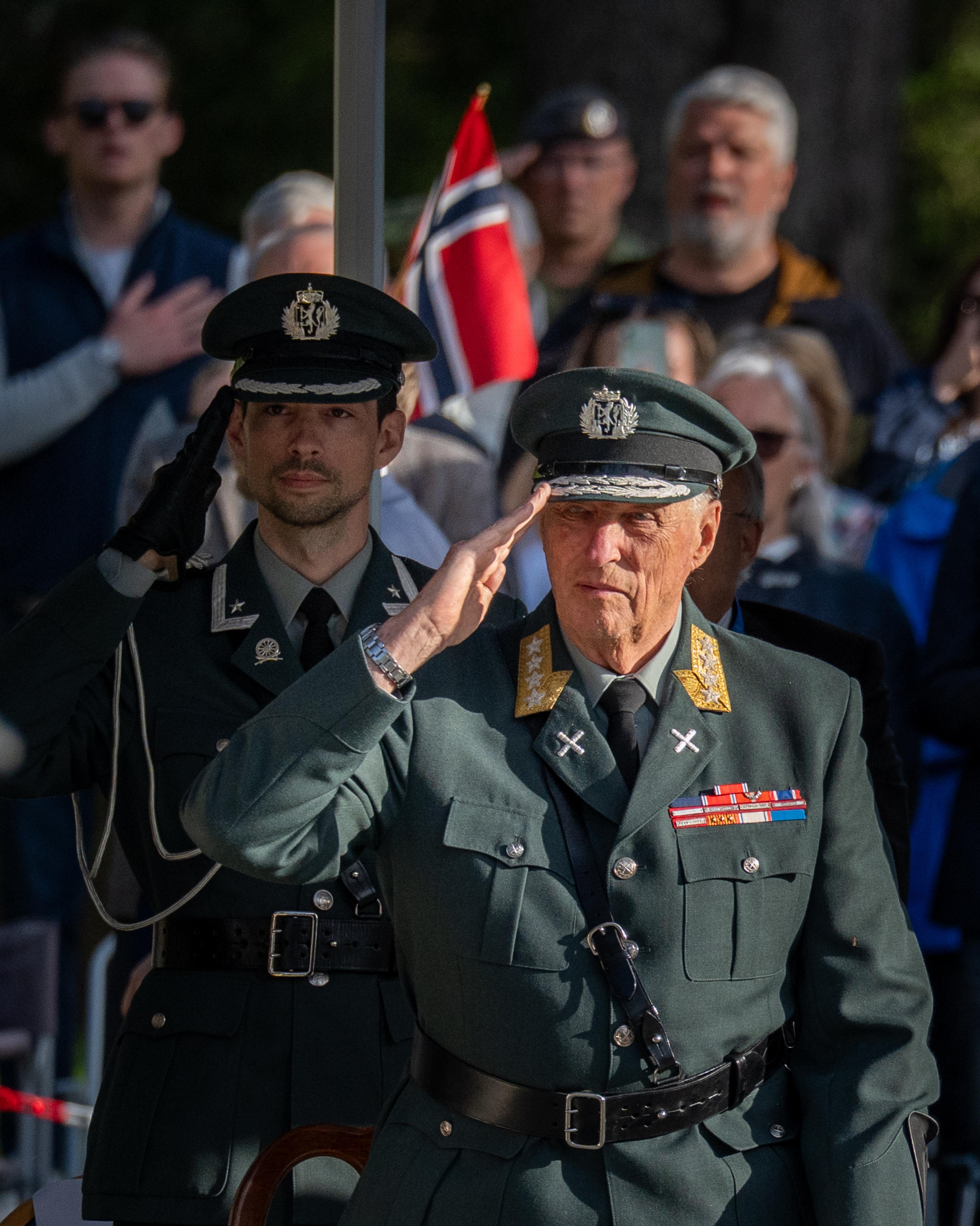 Kong Harald og Kongens adjutant gjør stående honnør iført Hærens tjenesteuniform.
