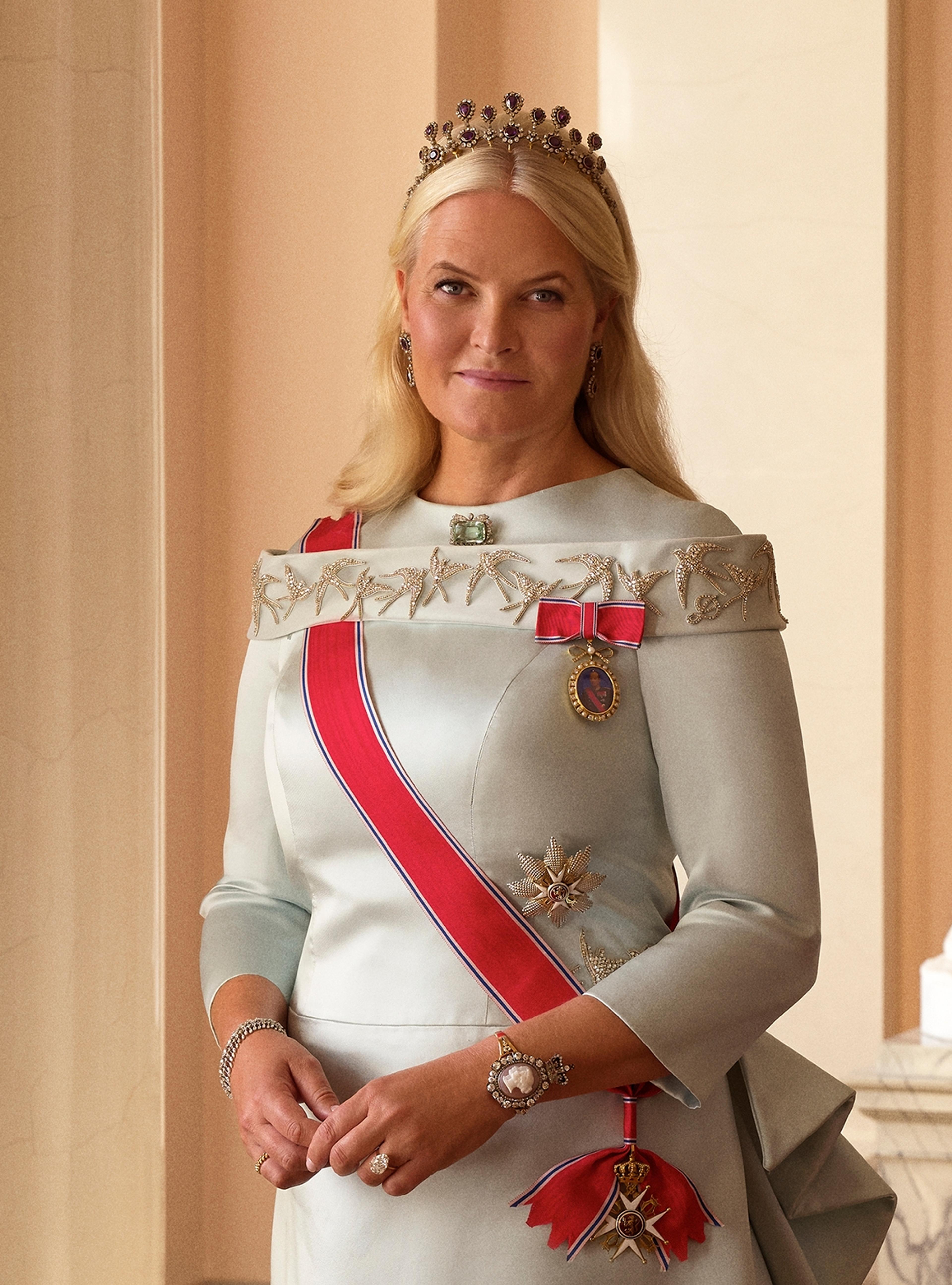 Kronprinsessen står i en lys gallakjole med ordener og diadem.