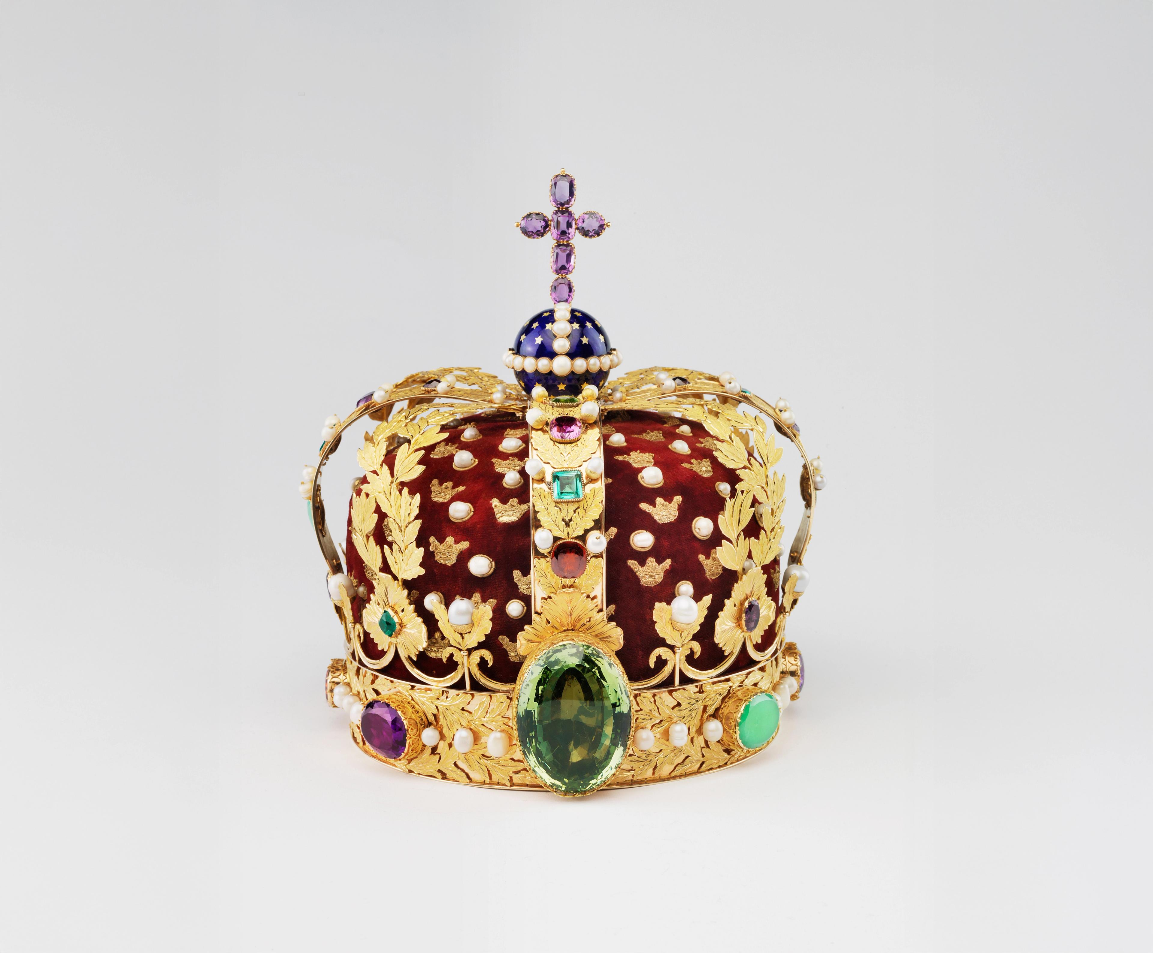 En bøylekrone i gull utsmykket med perler og edelstener og med purpurrød fløyelspull. Øverst en blå globe kronet med et kors av ametyster.