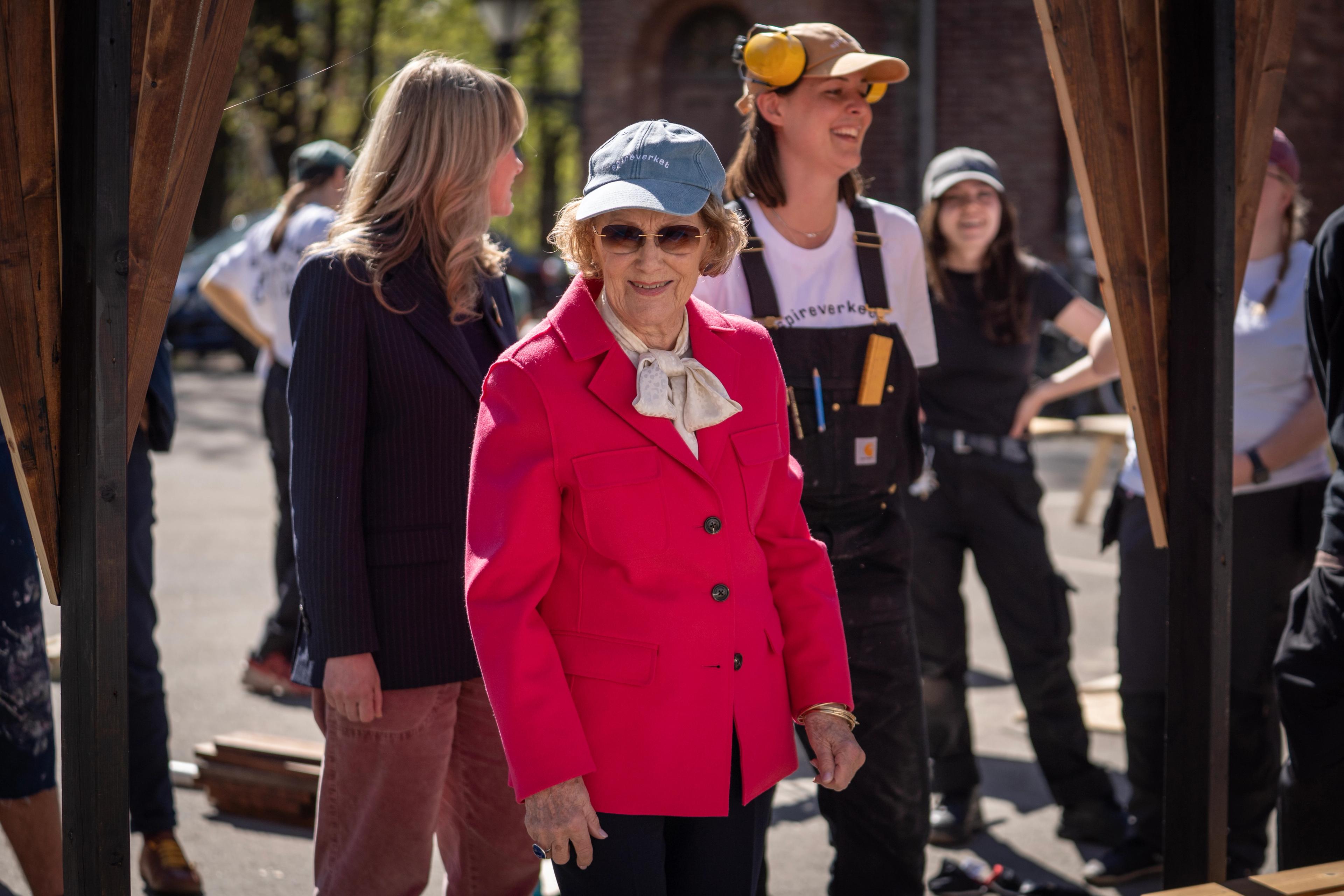 Dronning Sonja i pent antrekk og caps fra Spireverket.