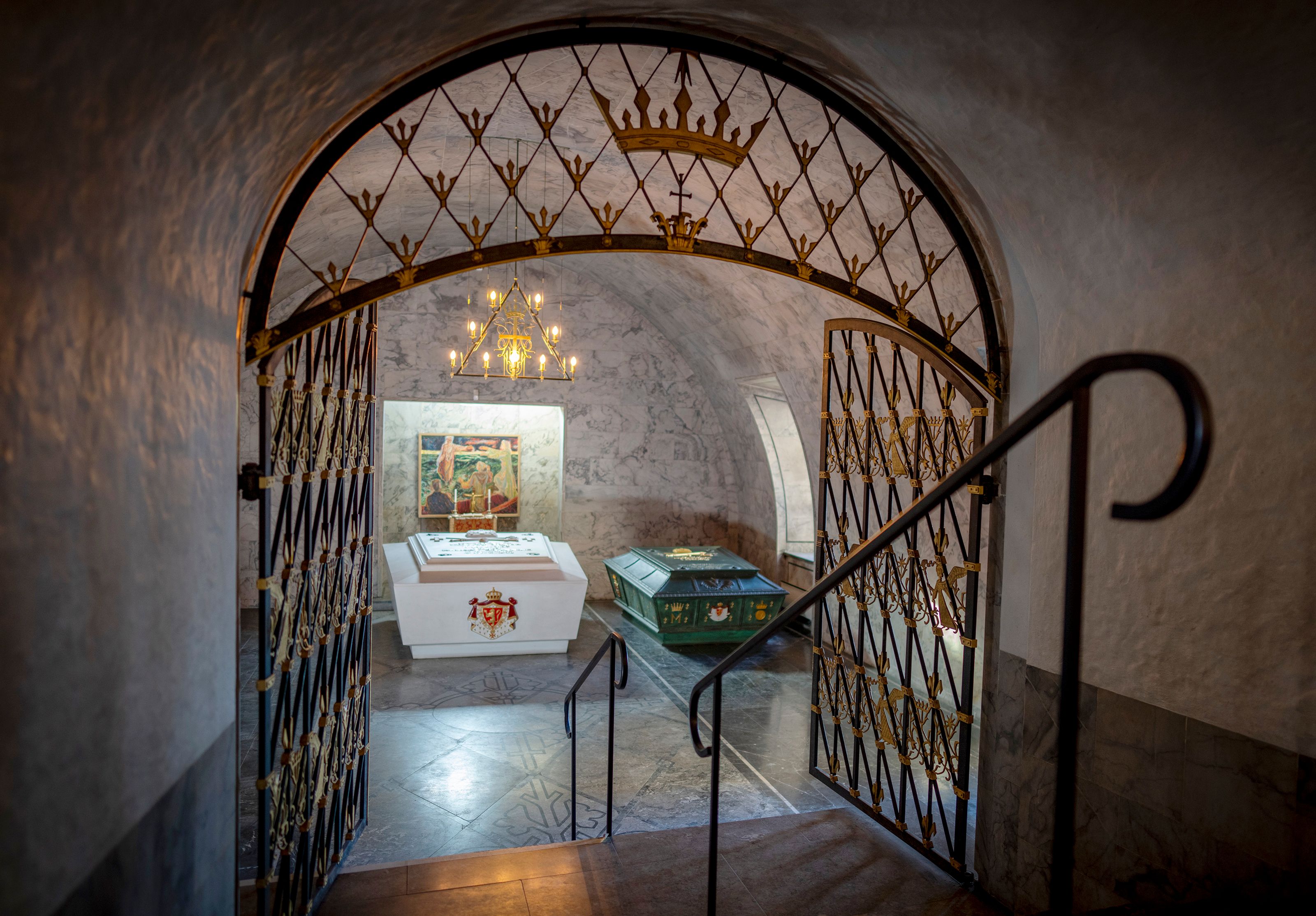 Gjennom en utsmykket gitterport ser vi de to sarkofagene i Det kongelige mausoleum. En hvit og en grønn.