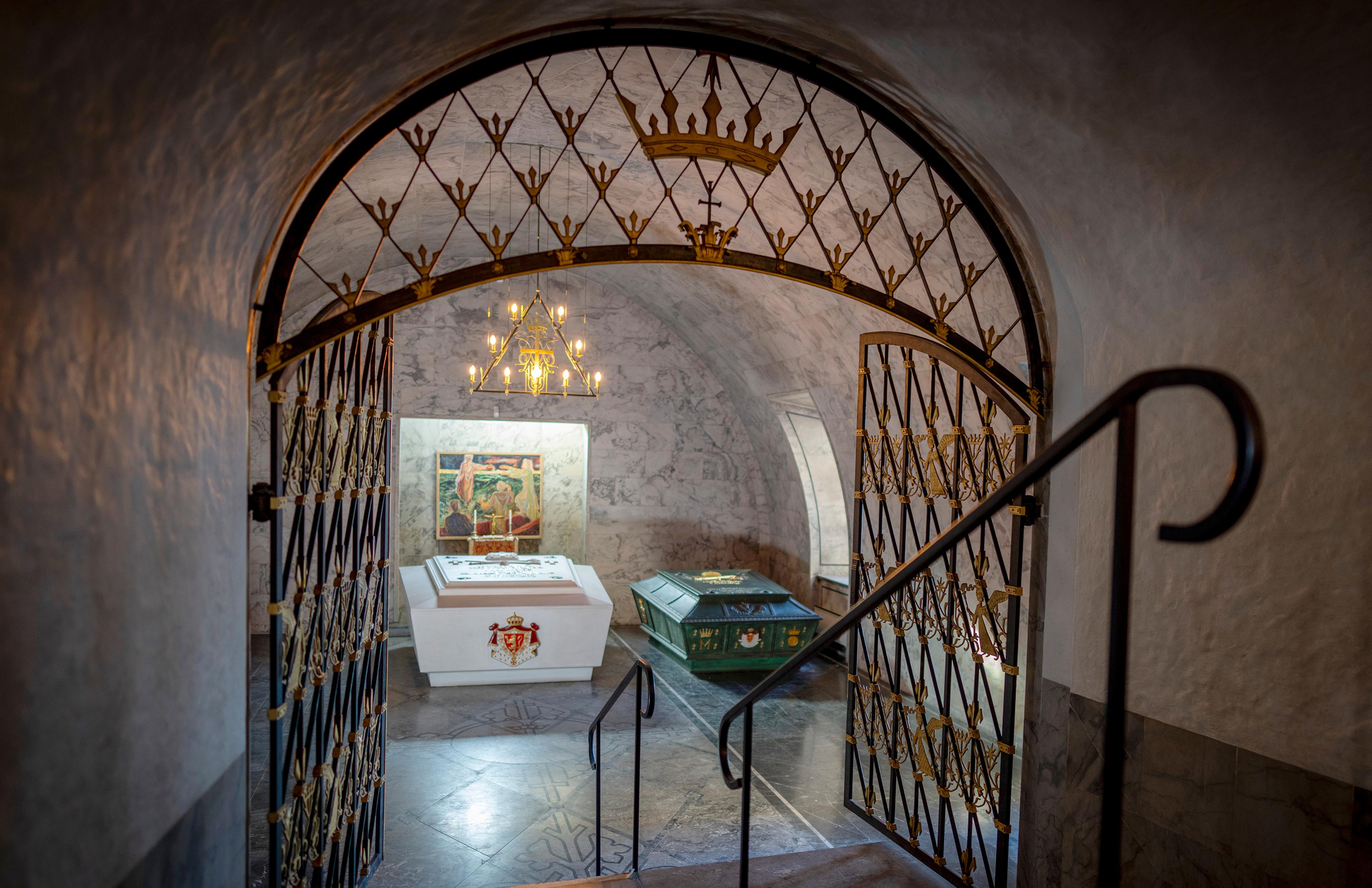 Gjennom en utsmykket gitterport ser vi de to sarkofagene i Det kongelige mausoleum. En hvit og en grønn.