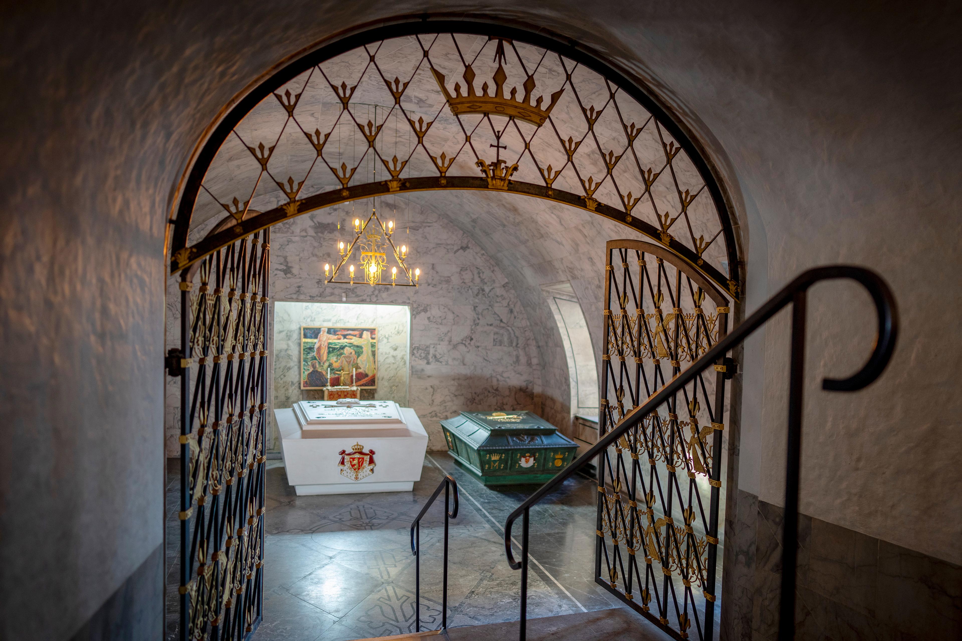 Gjennom en utsmykket gitterport ser vi de to sarkofagene i Det kongelige mausoleum. En hvit og en grønn.