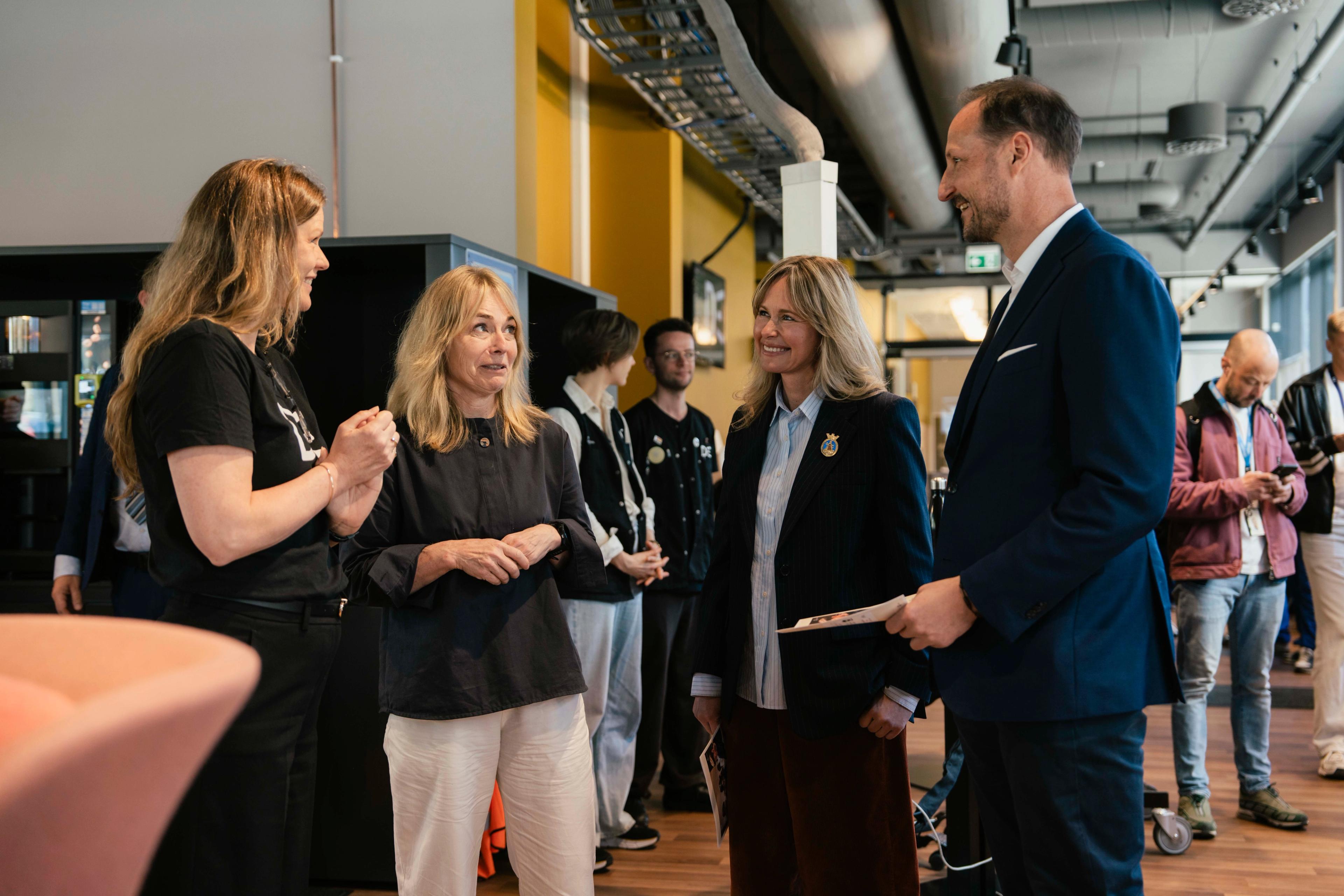 Kronprins Haakon står i en gruppe med mennesker inne på Deichman bibliotek på Lambertseter