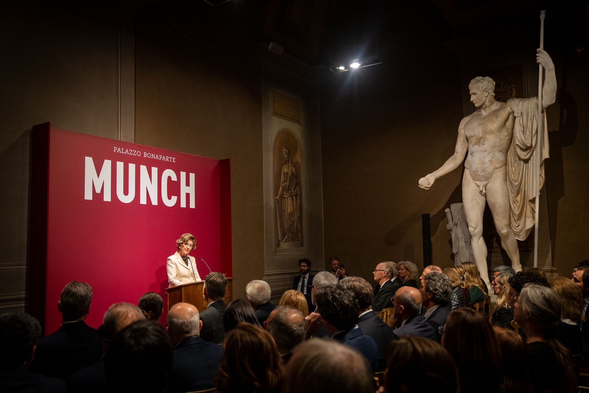 Dronningen taler for en større forsamling - inklusive en klassisk statue.