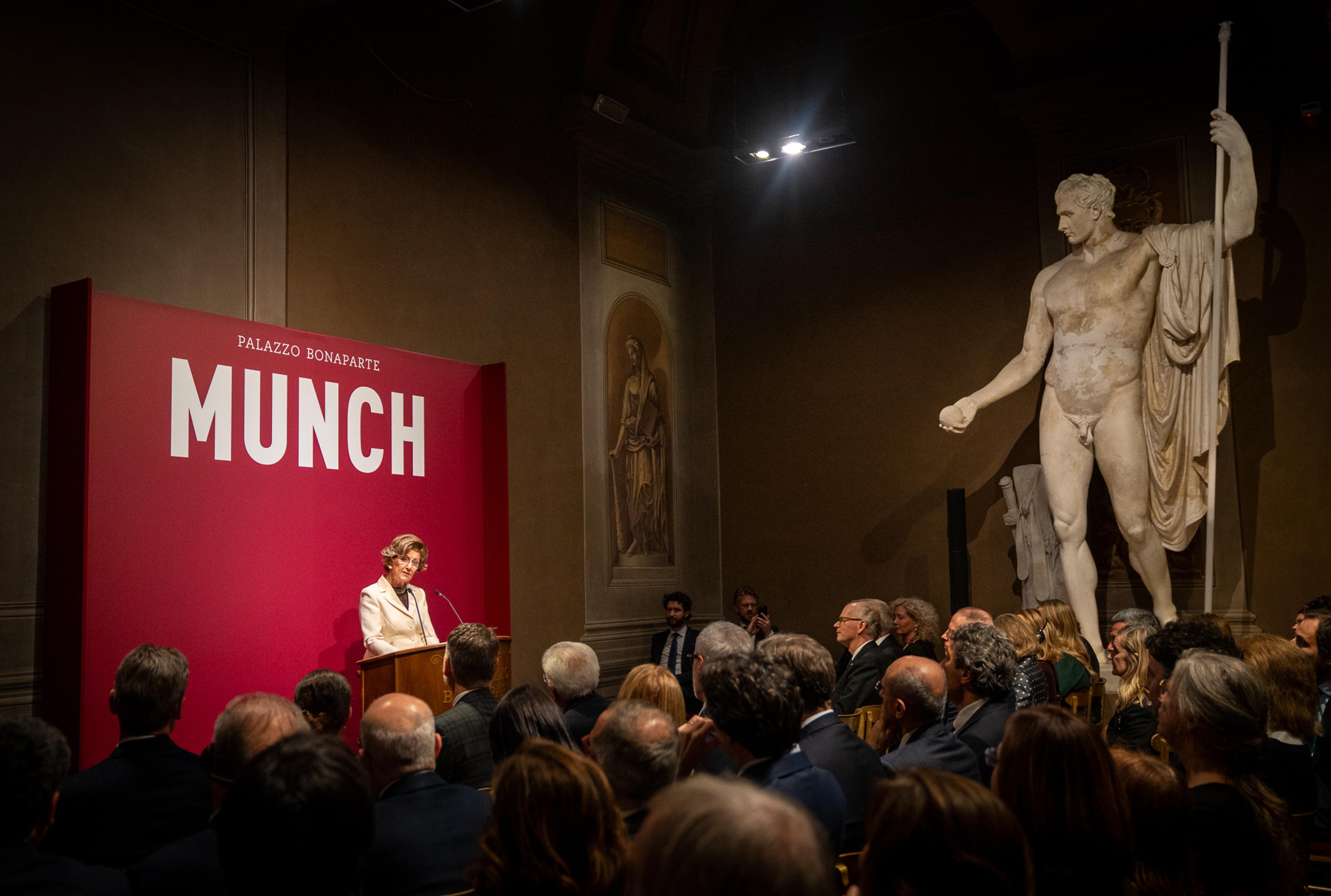Dronningen taler for en større forsamling - inklusive en klassisk statue.
