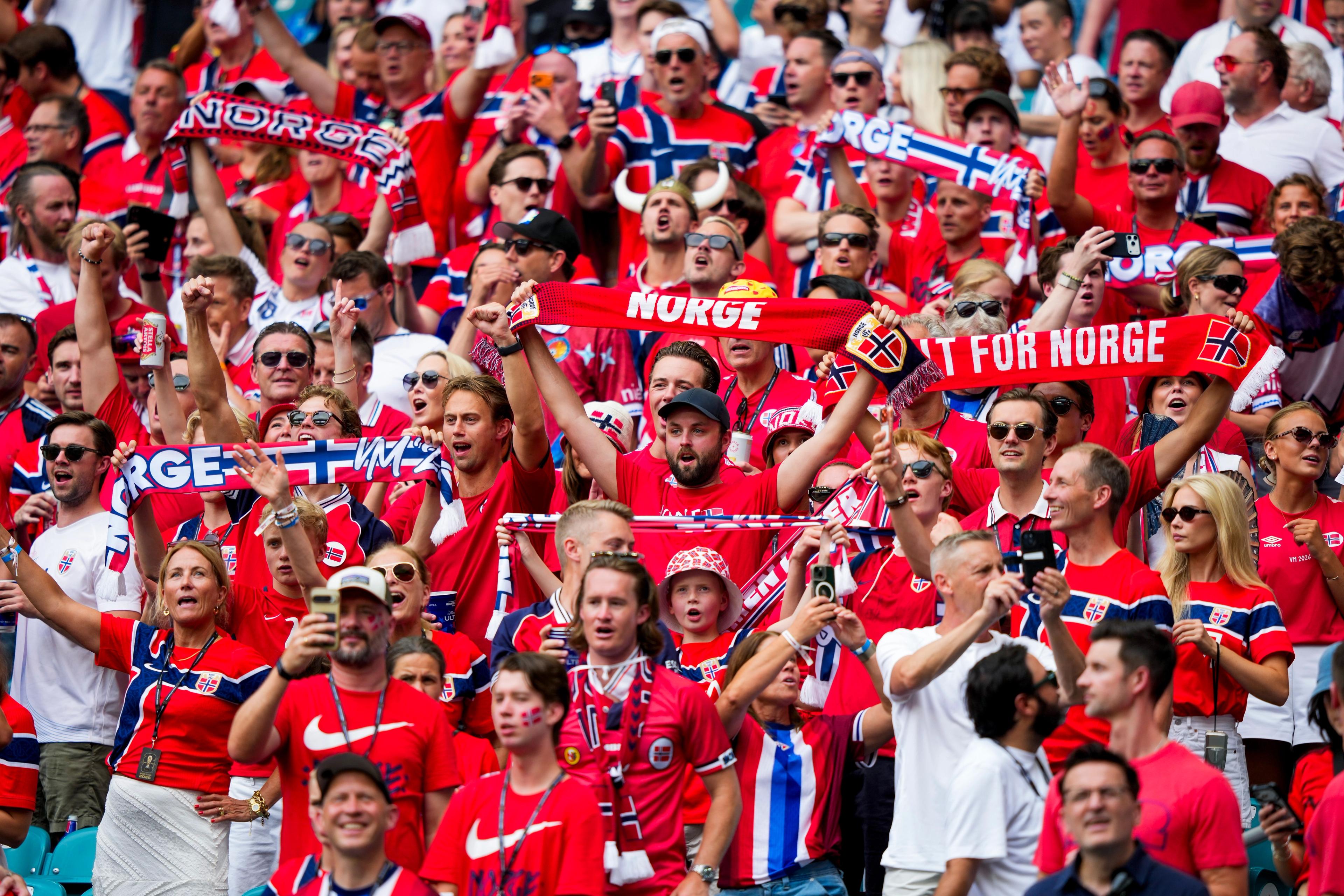 Flere av supporterne holder Norge-skjerf over hodet.