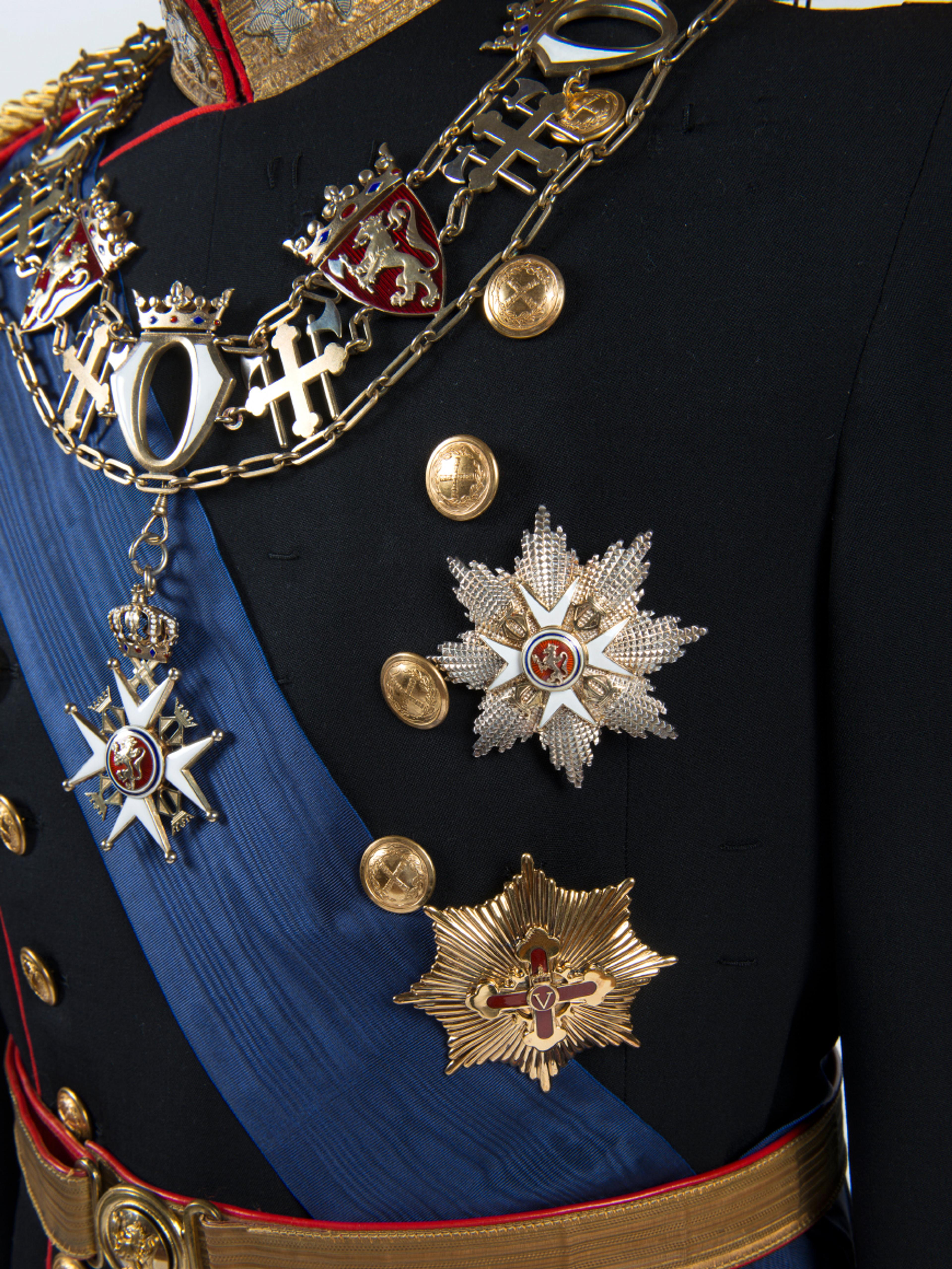 Nærbilde av jakken til Kong Haralds gallauninform med kjedet til St. Olavs Orden og krasjanen fra både St. Olavs Orden og Fortjenstordenen.