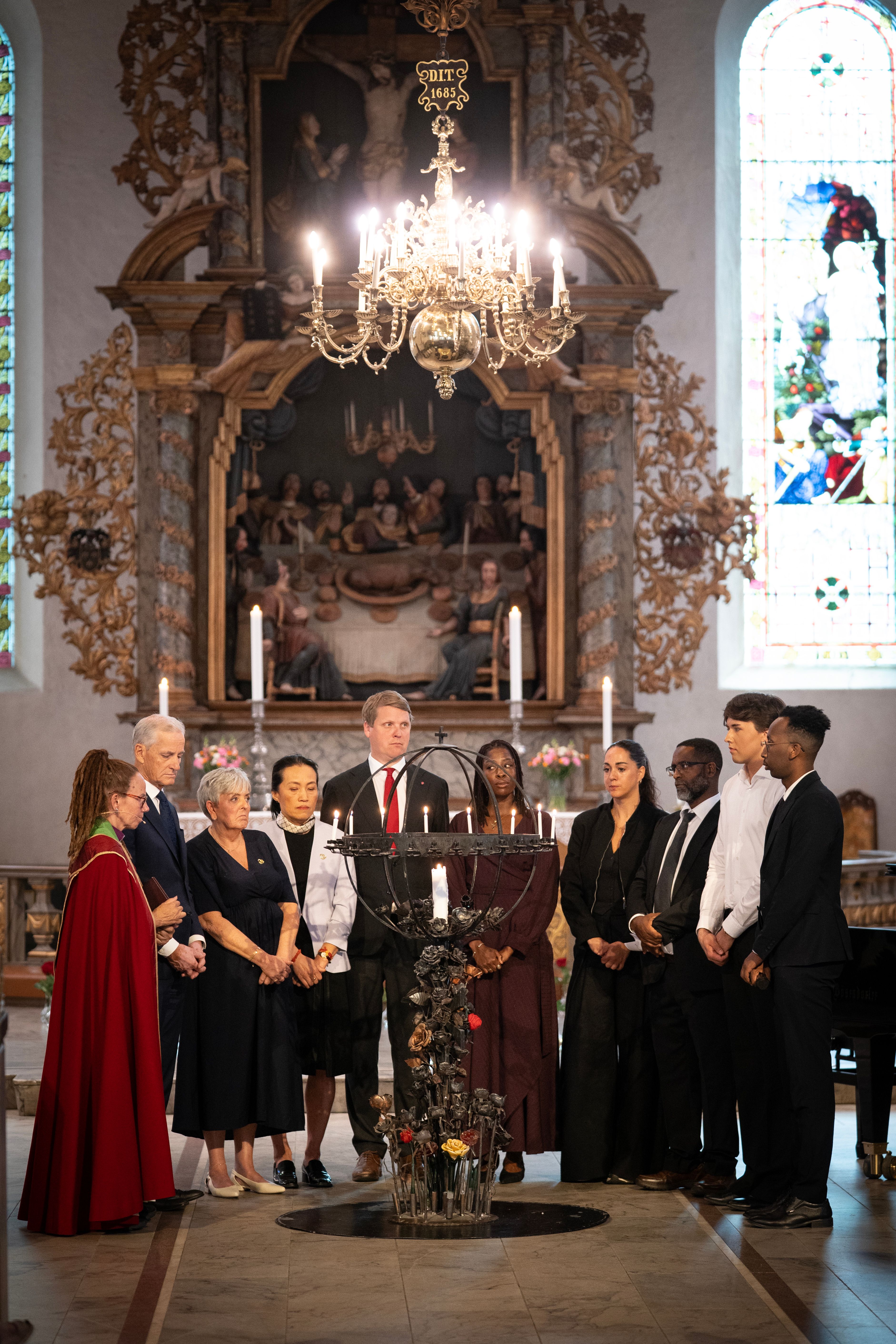 En gruppe mennesker er samlet for å tenne lys i en kirke