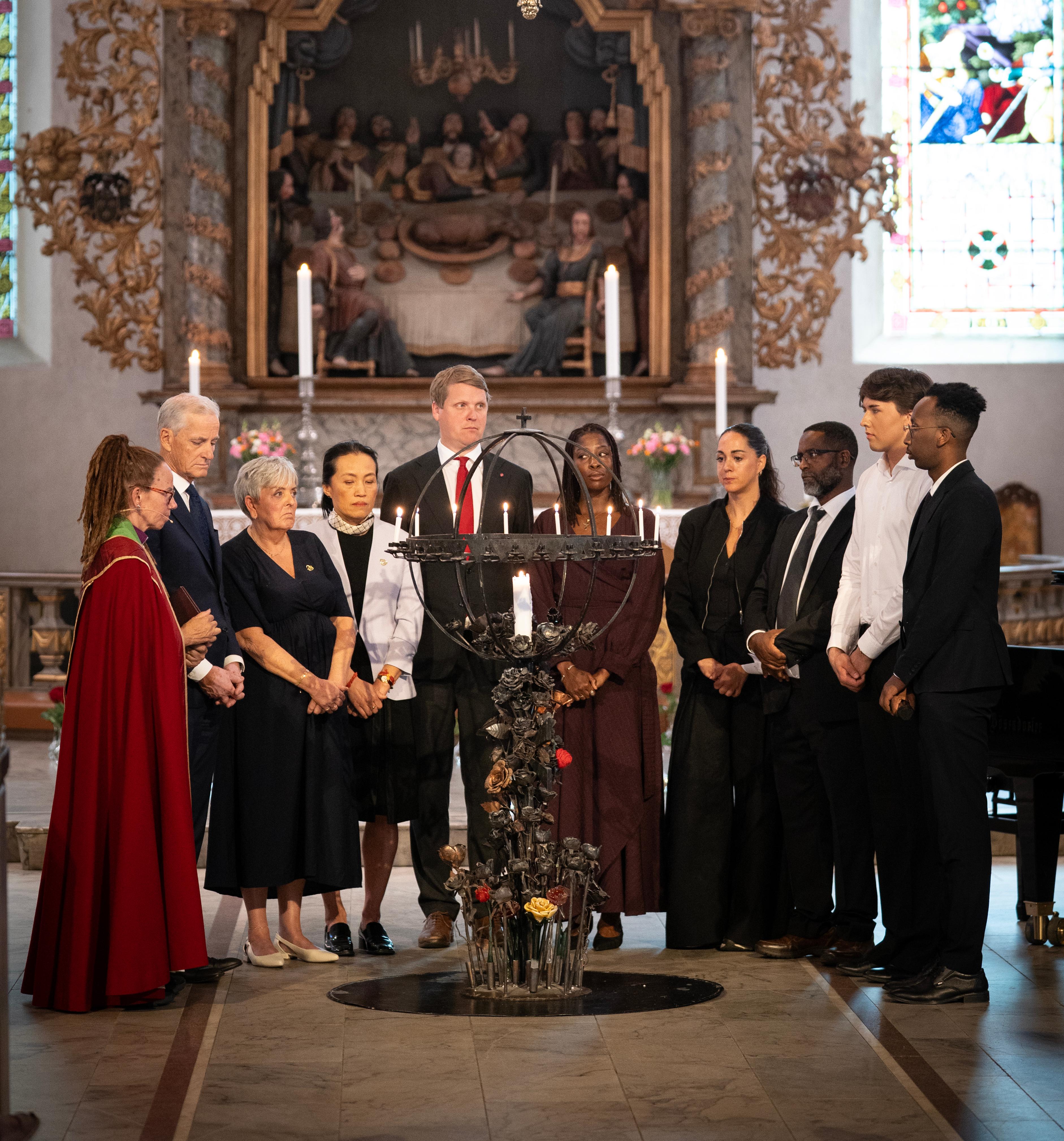 En gruppe mennesker er samlet for å tenne lys i en kirke