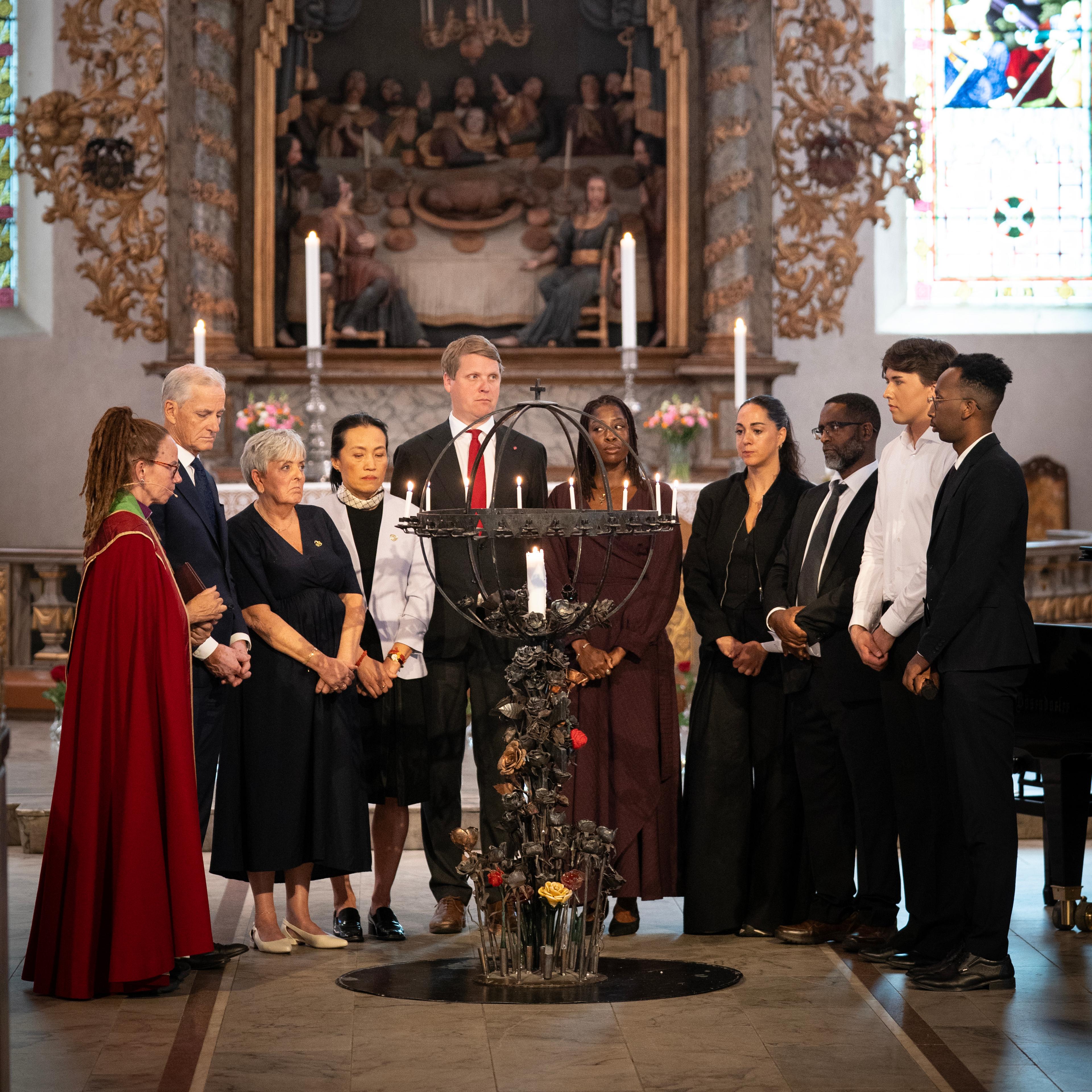 En gruppe mennesker er samlet for å tenne lys i en kirke