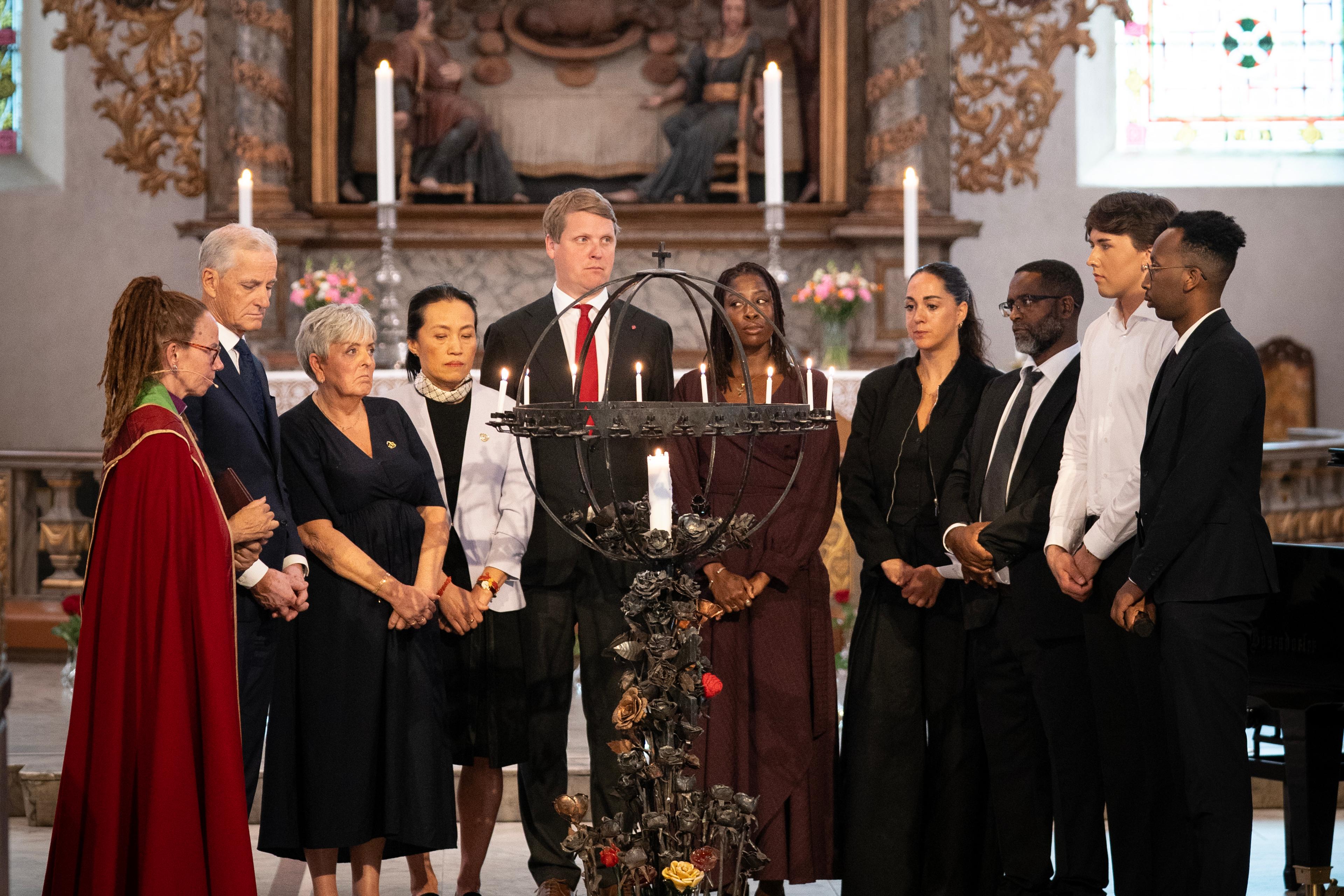 En gruppe mennesker er samlet for å tenne lys i en kirke