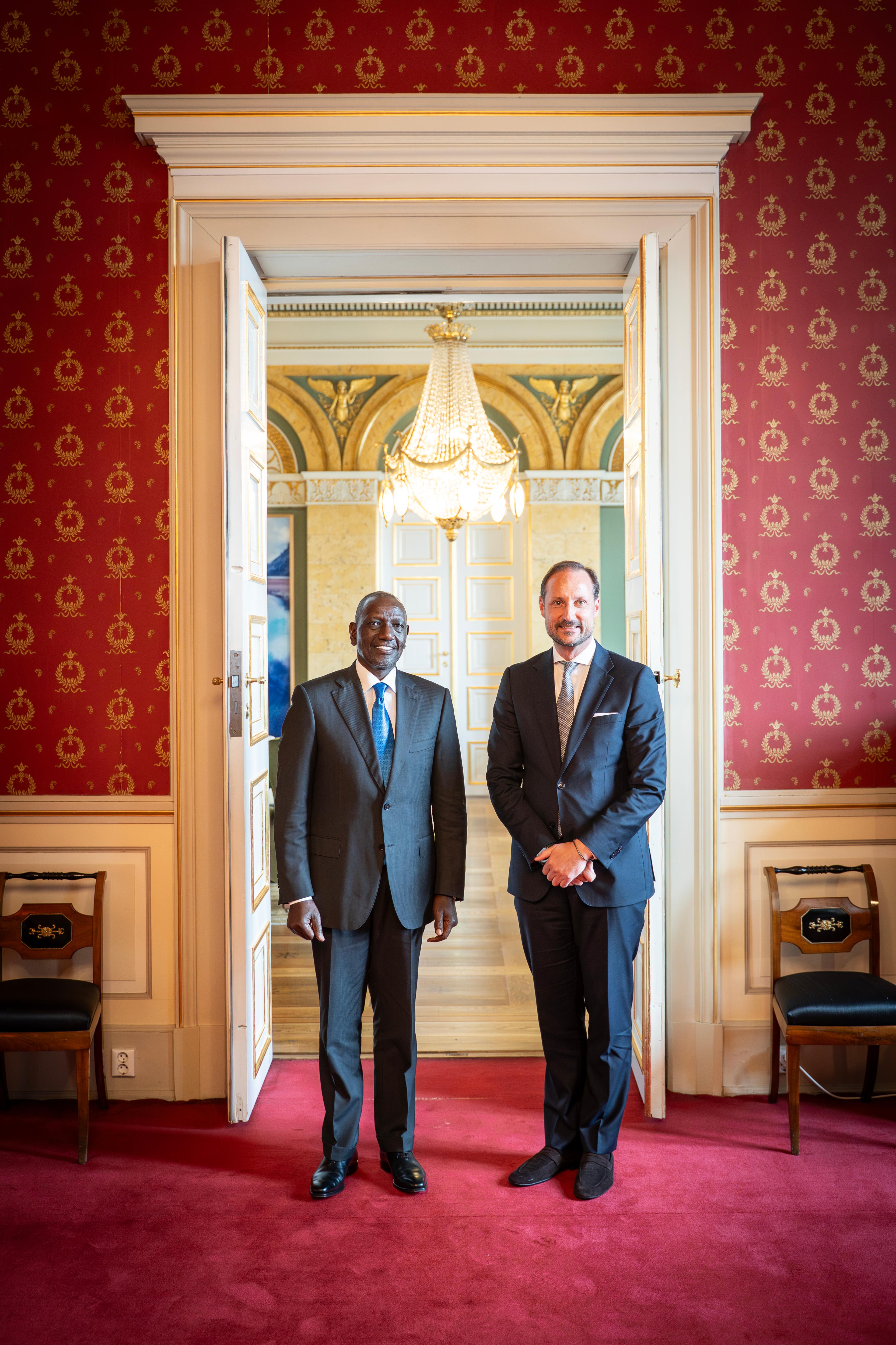 Kronprins Haakon og Kenyas president står smilende i dress, vendt mot kamera.