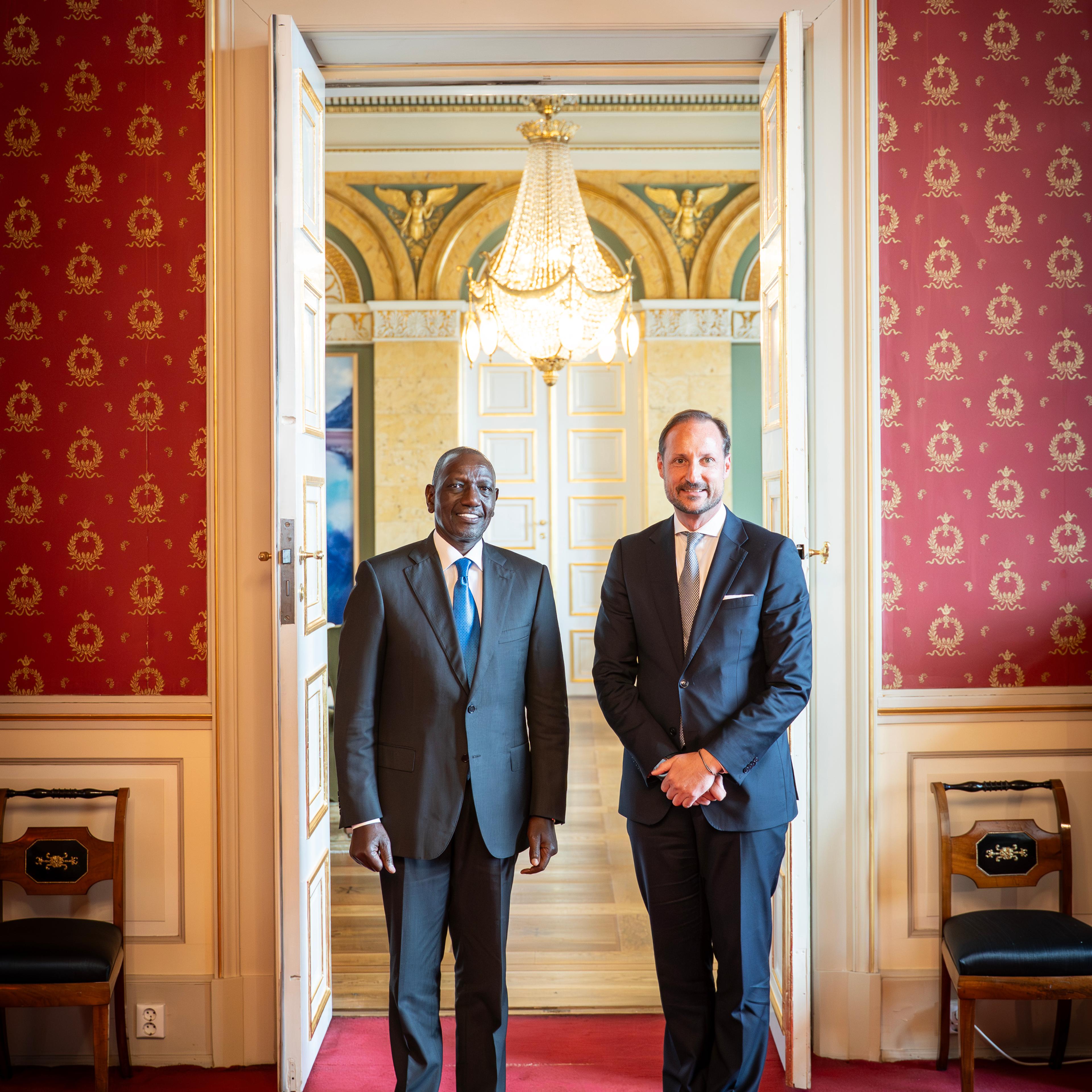 Kronprins Haakon og Kenyas president står smilende i dress, vendt mot kamera.