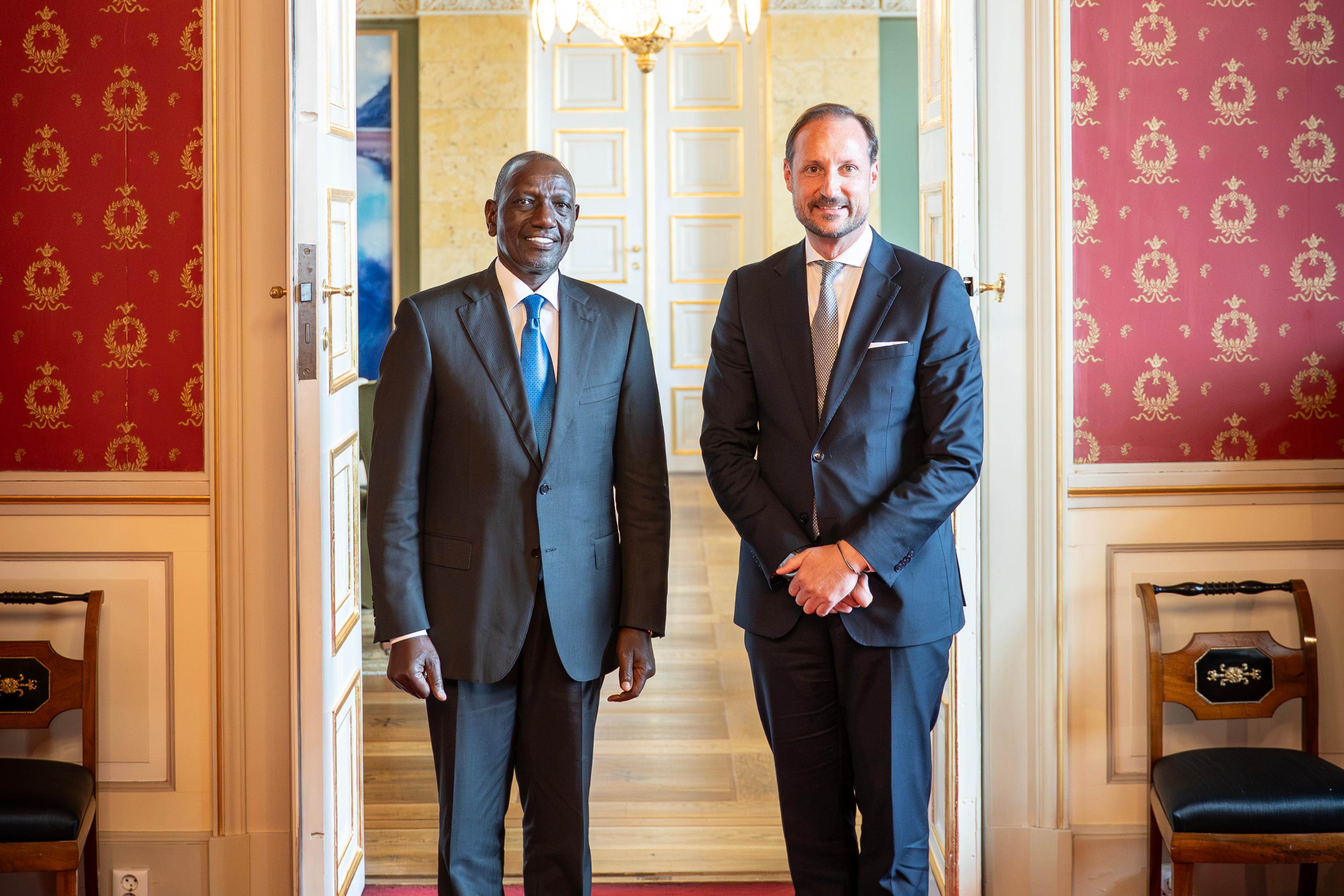 Kronprins Haakon og Kenyas president står smilende i dress, vendt mot kamera.