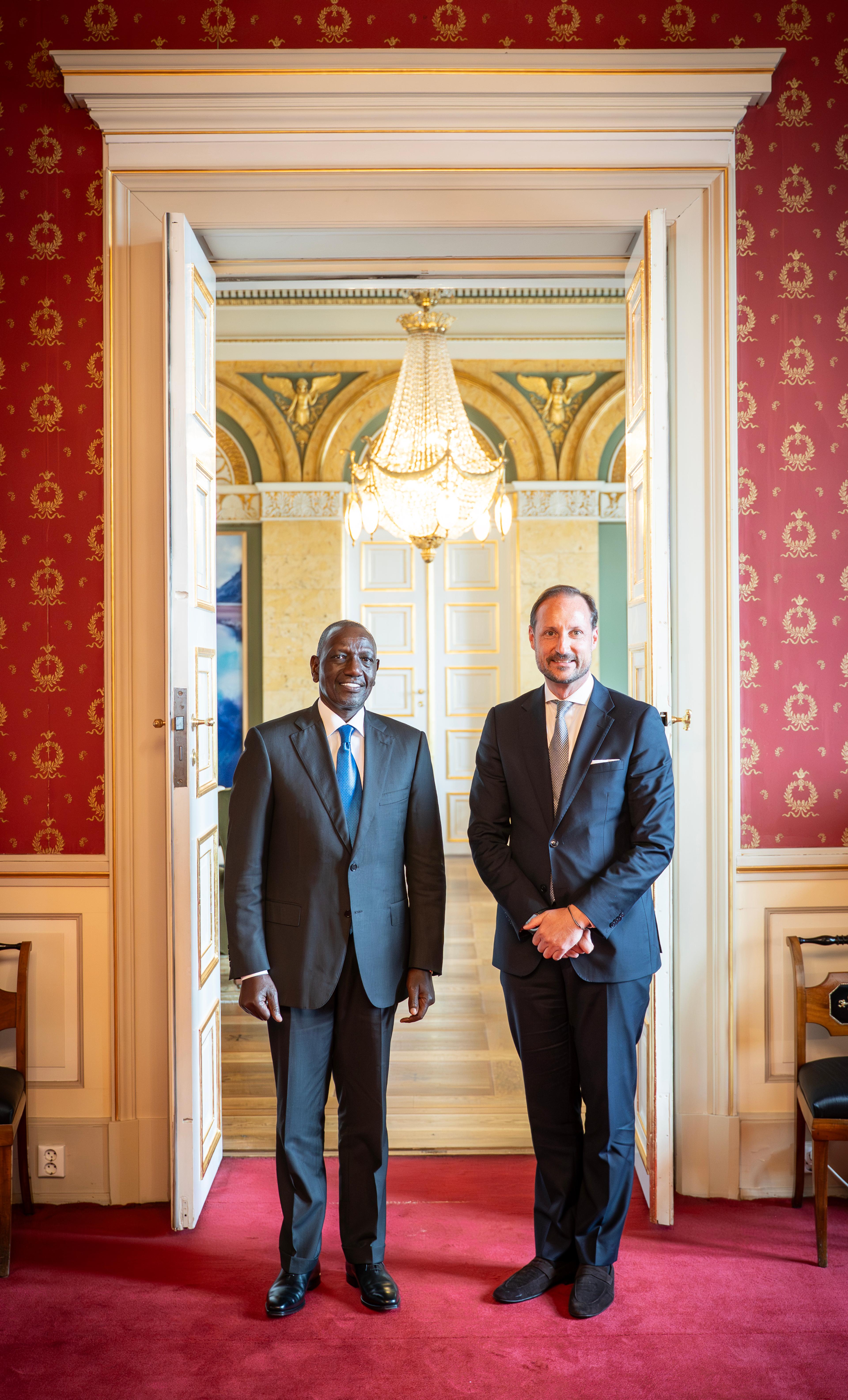 Kronprins Haakon og Kenyas president står smilende i dress, vendt mot kamera.