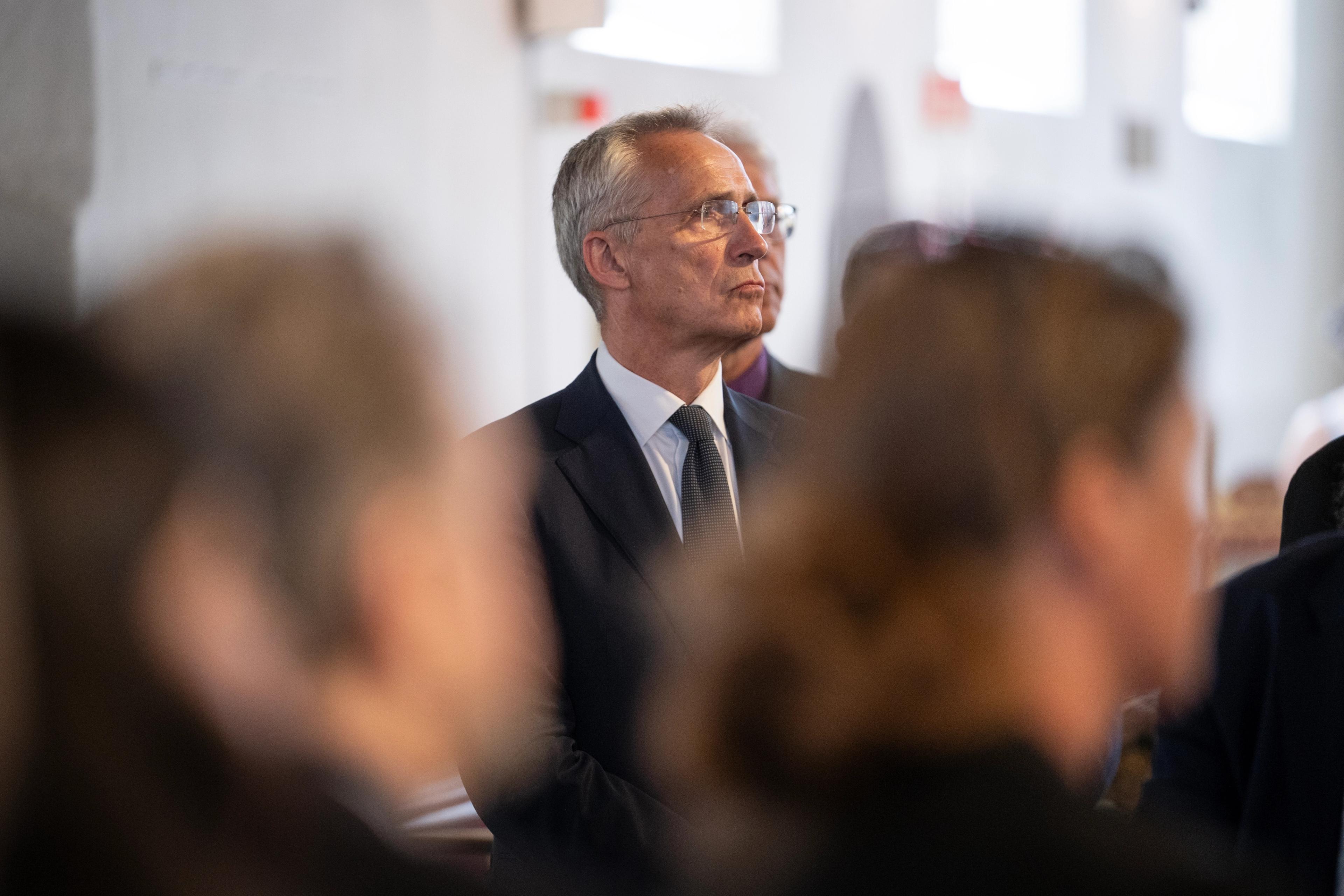 Jens Stoltenberg står oppreist og ser mot midtgangen av kirken