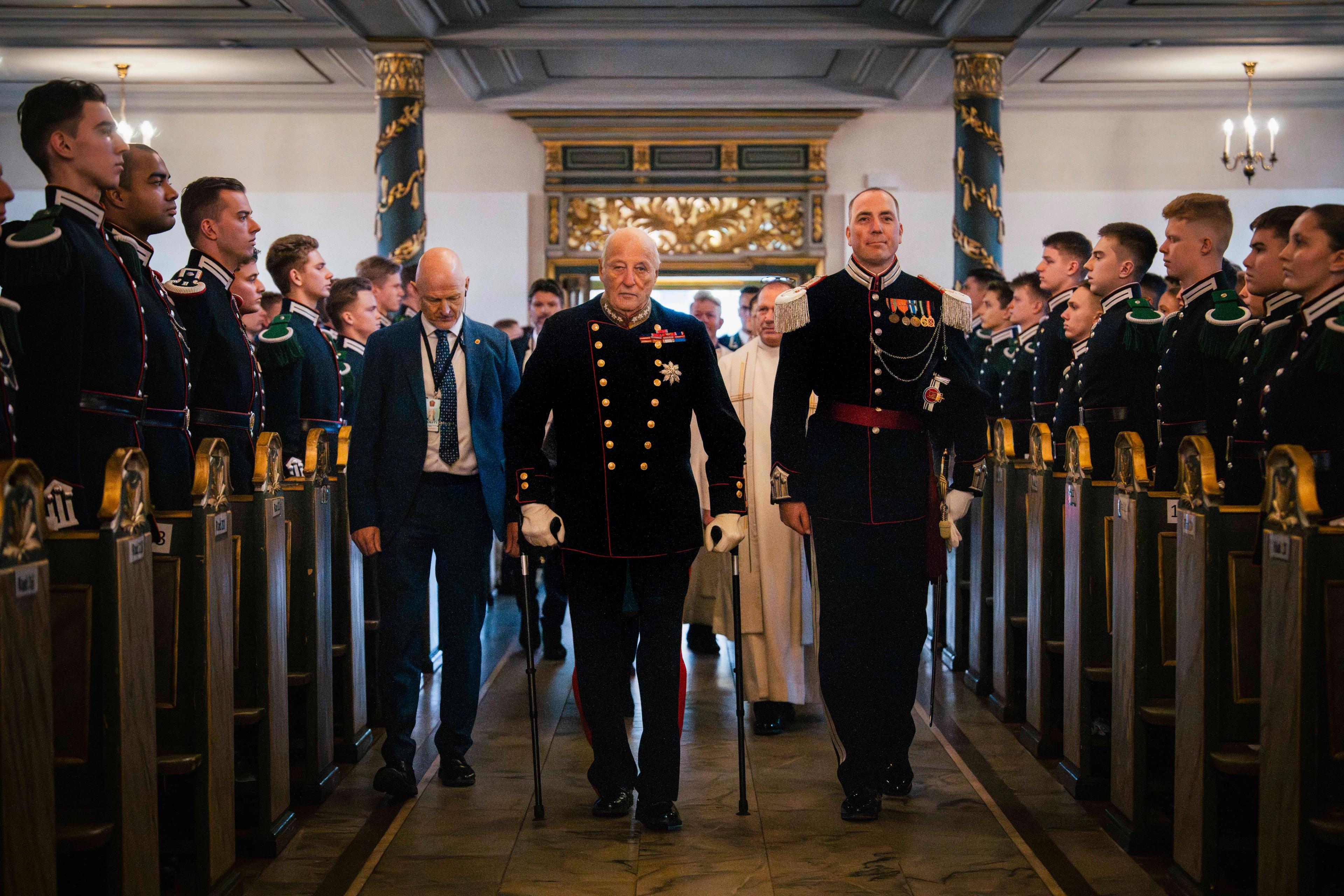 Kong Harald og gardesjef Henrik Hove går fremst i ein prosesjon, medan gardistar står oppstilte på kvar side langs kyrkjebenkene.